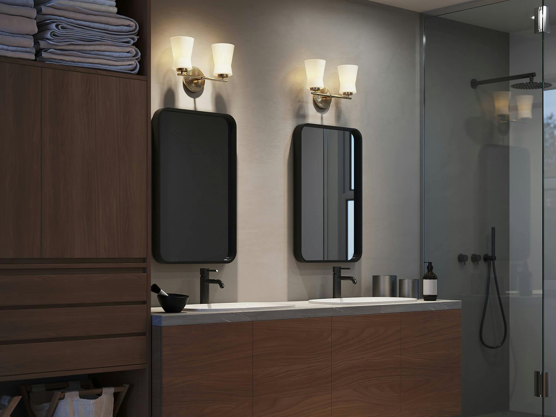 Nighttime bathroom scene with two mirrors, a Brianne sconce shining above each