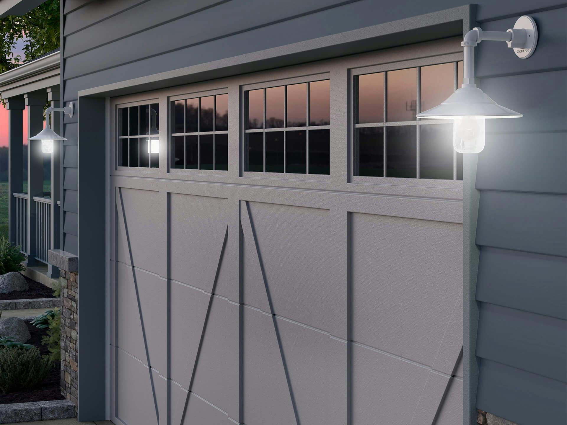 Exterior image of a garage at the front of a house with exterior wall lights lighting up the garage in the evening time 