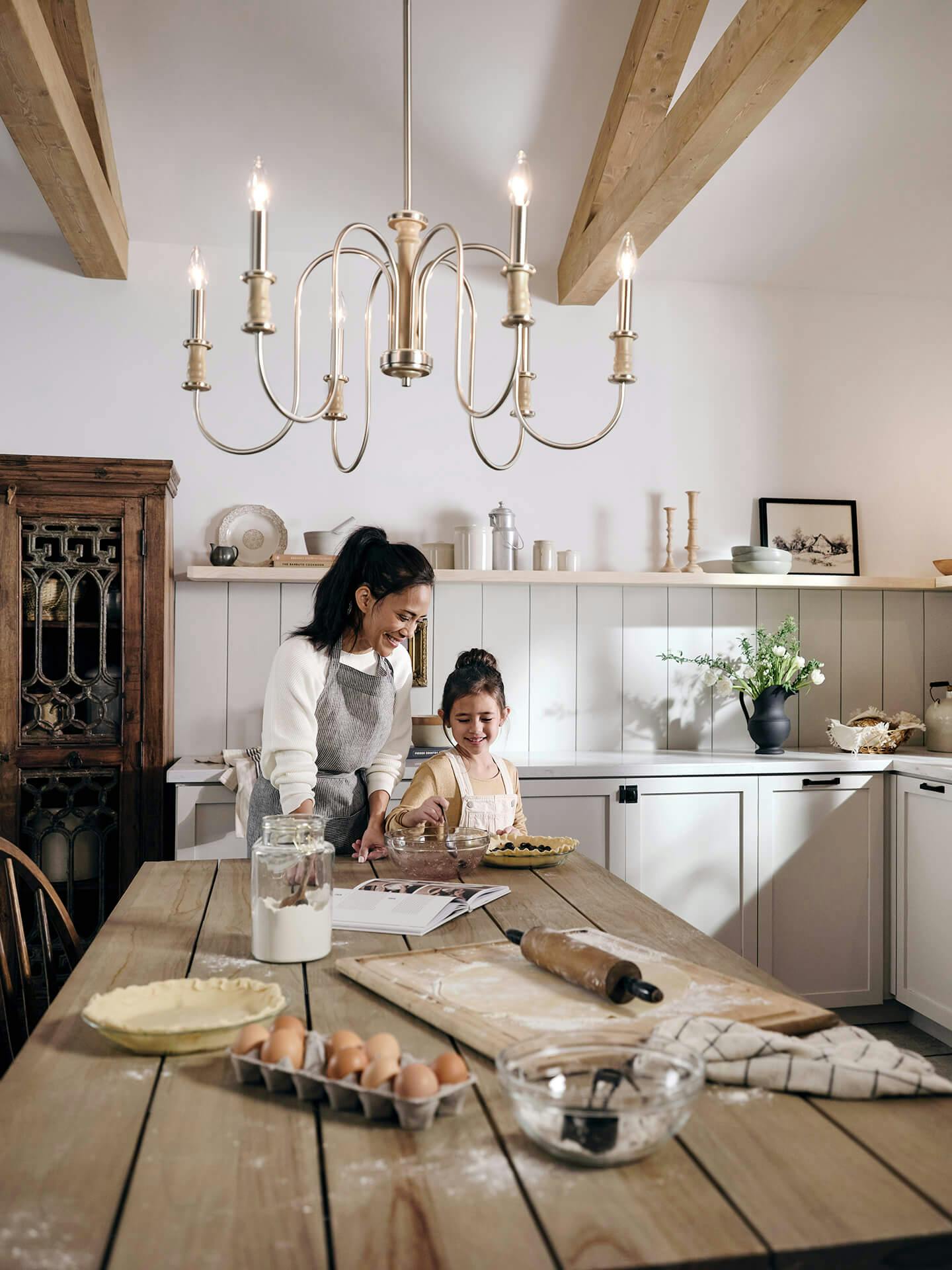 Mom and daughter baking in a rustic kitchen featuring a Karthe chandelier