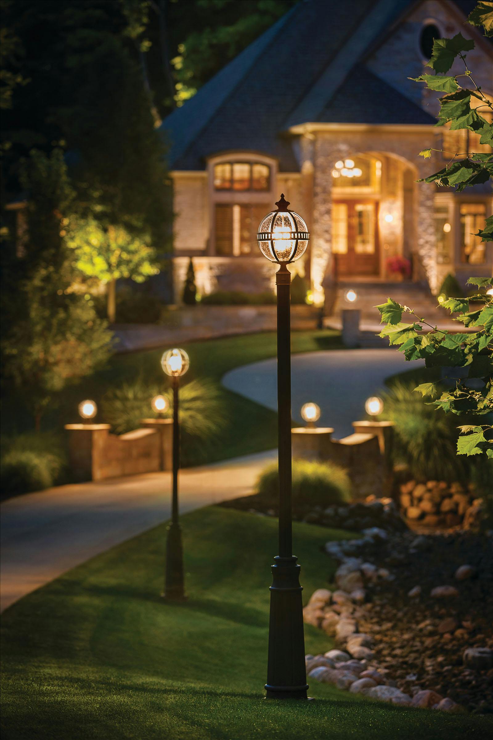 Night time driveway flanked by Halleron post lights and an illuminated home in the background