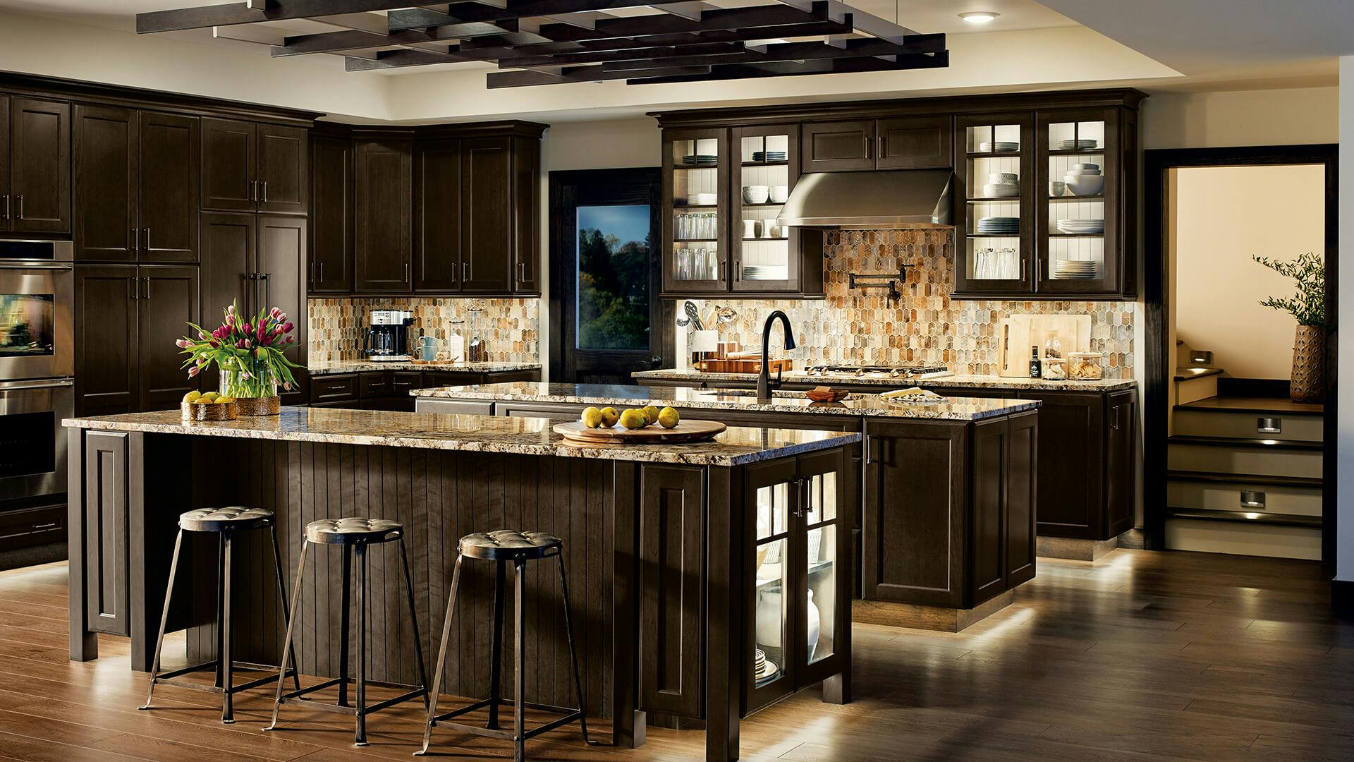 Kitchen with two islands featuring variety of lights above, toe lights and cabinet lights.