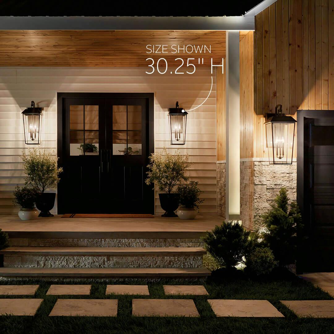 Porch at dusk featuring the Mathus 30.25" 3 Light Outdoor Wall Light with Clear Glass in Olde Bronze