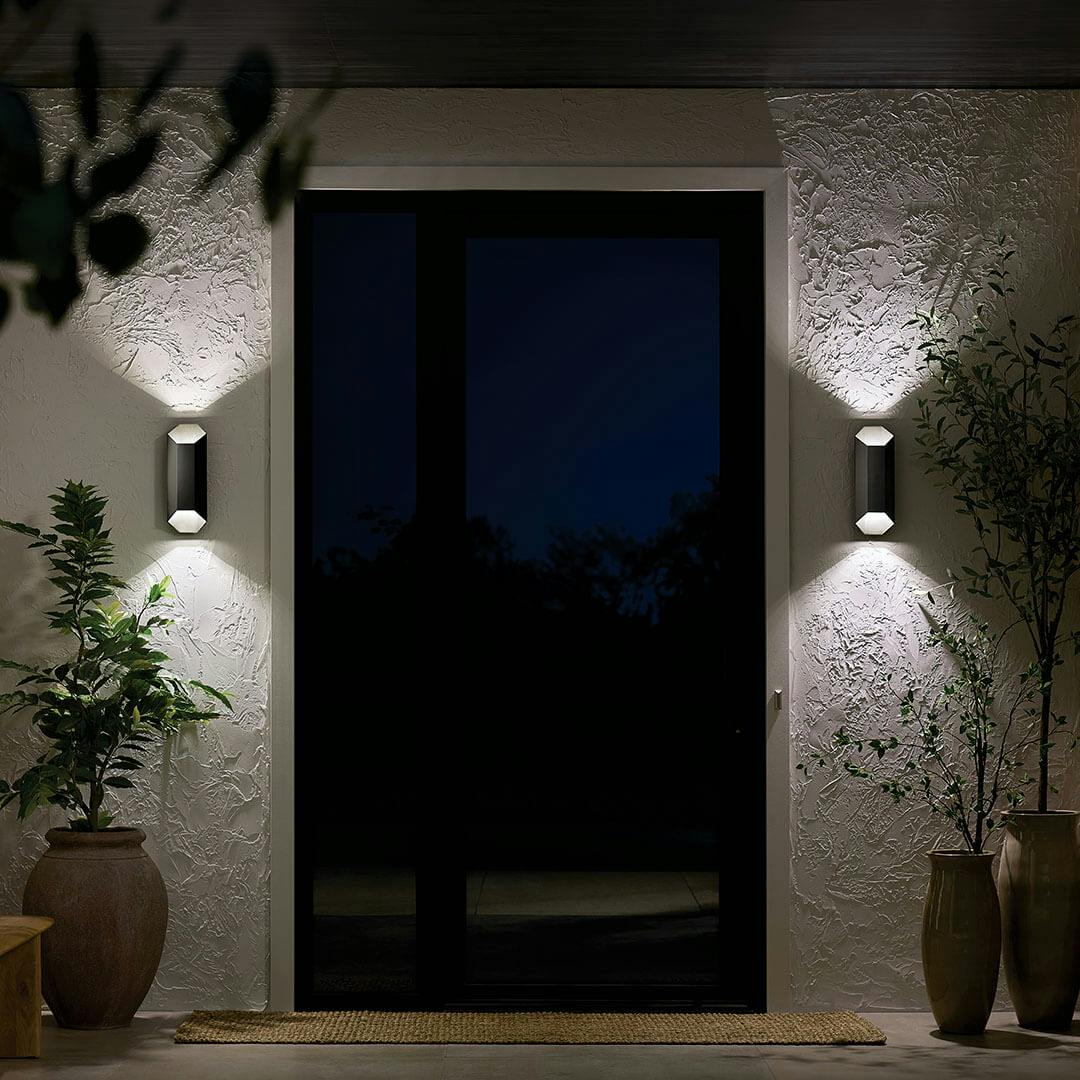 Night time view of the Estella 12" LED 1-Light Outdoor Wall Light in Black on the exterior of a home