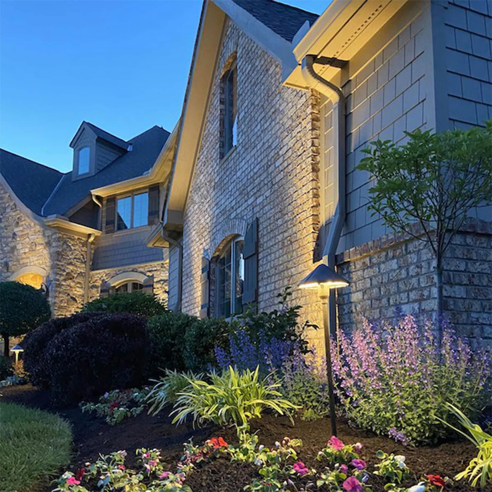 View of exterior of home at dusk, path lighting and exterior lighting is on.