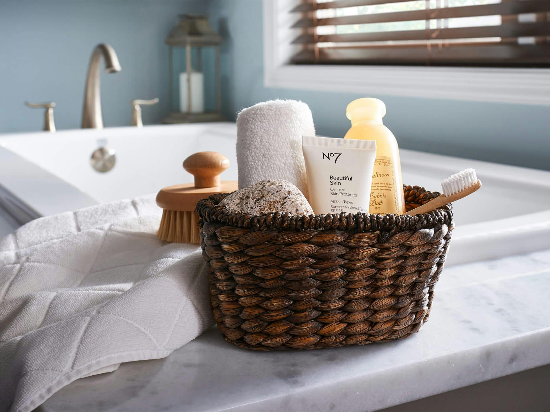 basket of self care goodies on ledge of bathtub