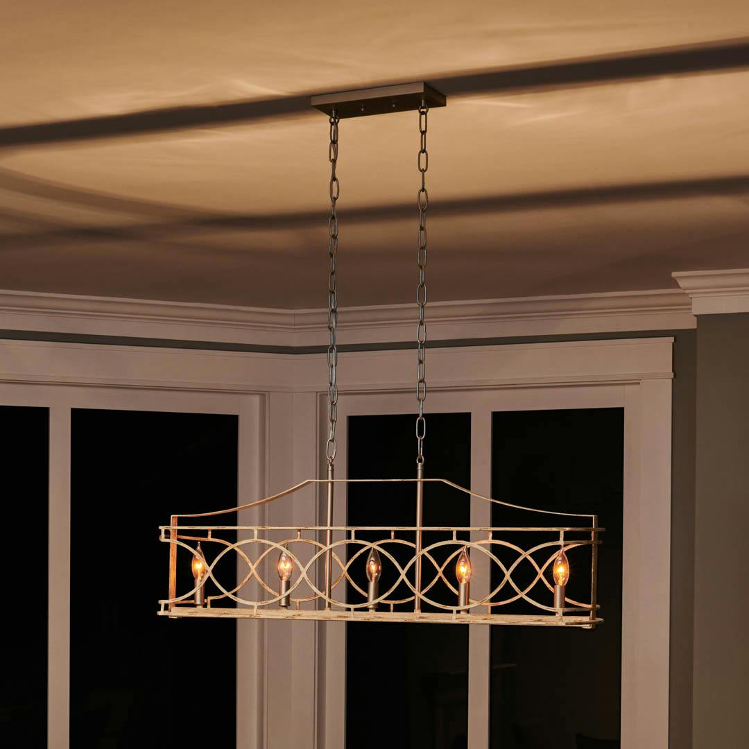 Night time dining room with Adelgade 5 Light Linear Chandelier in Distressed Antique White and Brushed Nickel