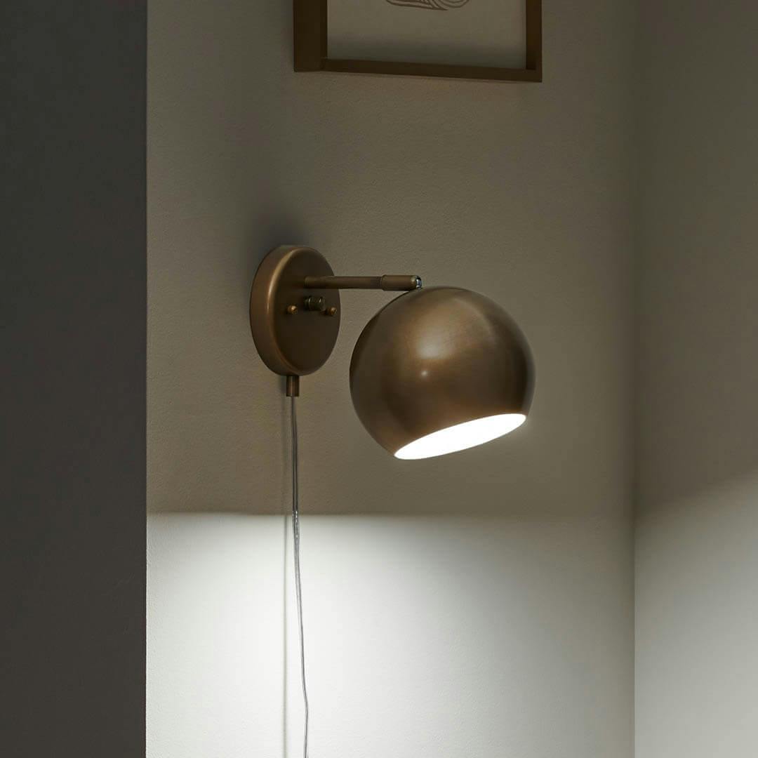 Night time reading nook with Lemmy 7.5 Inch 1 Light Plug-In Wall Sconce in Natural Brass