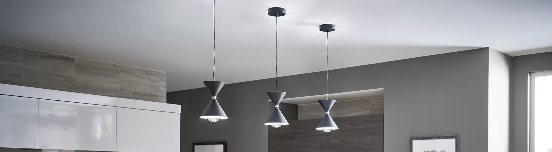 Three matte black Kordan pendants hanging from a kitchen ceiling