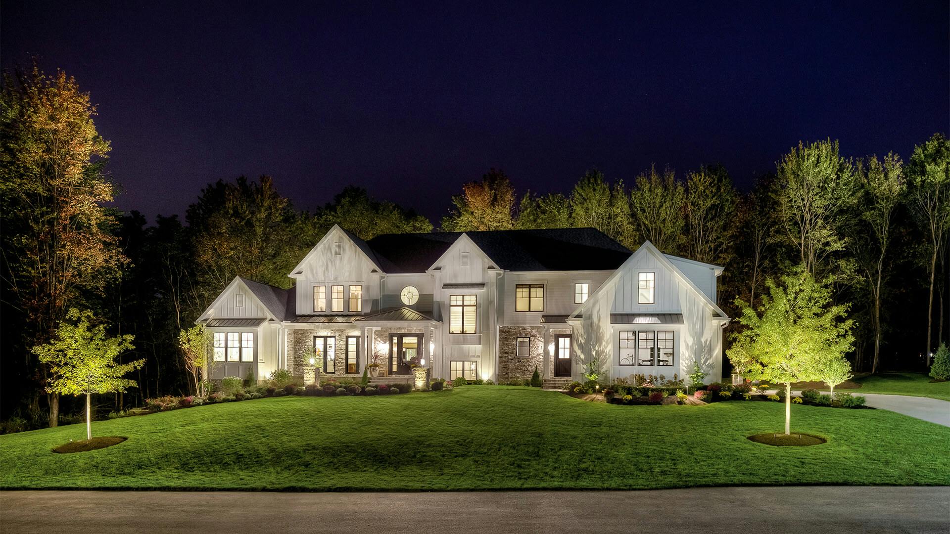 Modern farmhouse at night with landscape lighting