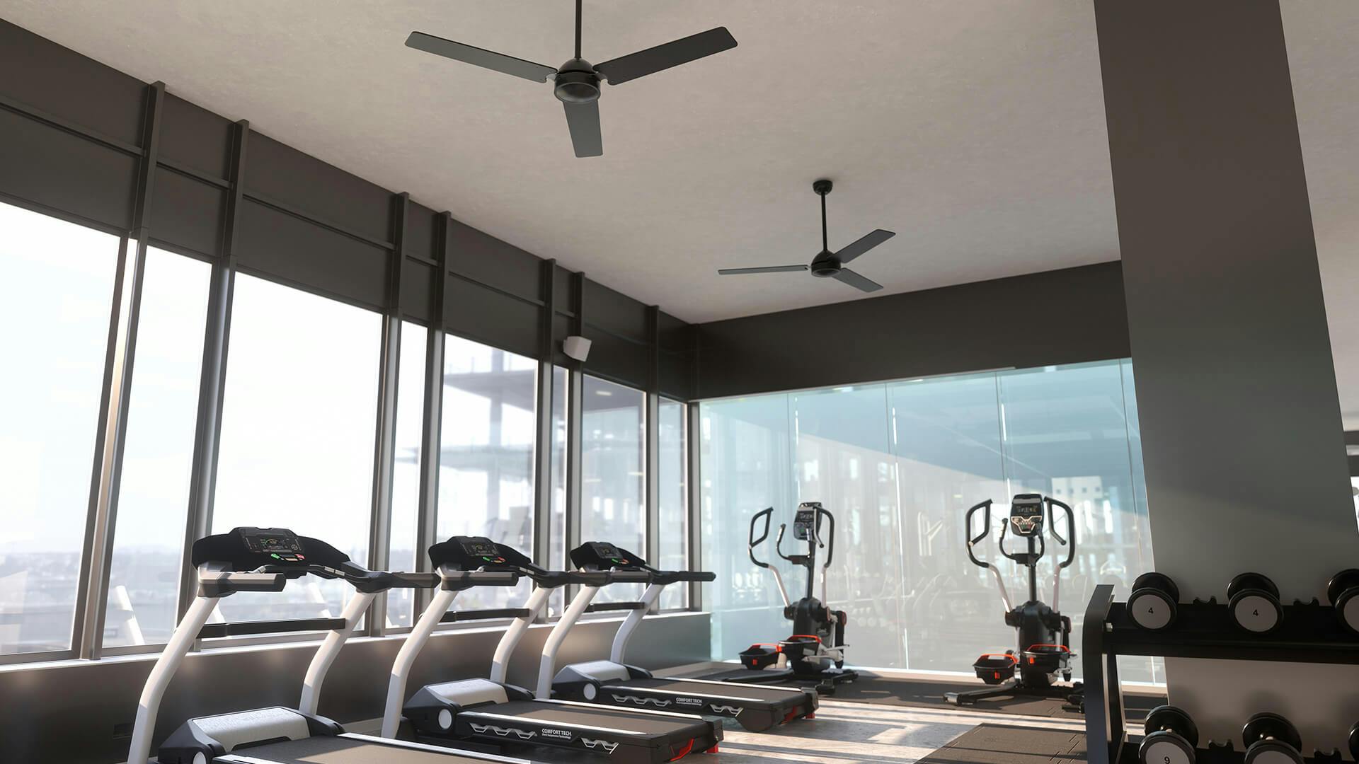 Hotel gym on a higher up floor in a city, featuring ceiling fans
