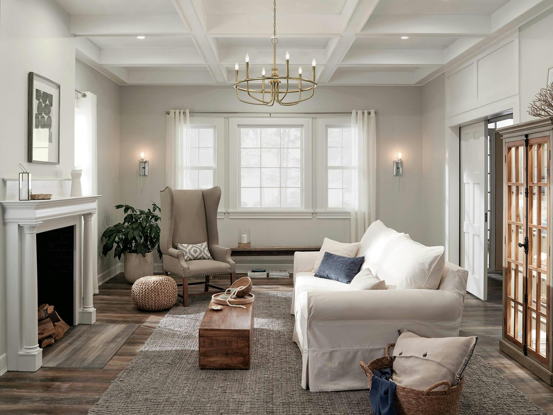 Living room at day with white walls featuring two silver Alton sconces on the back wall while a gold Capitol Hill chandelier hangs above