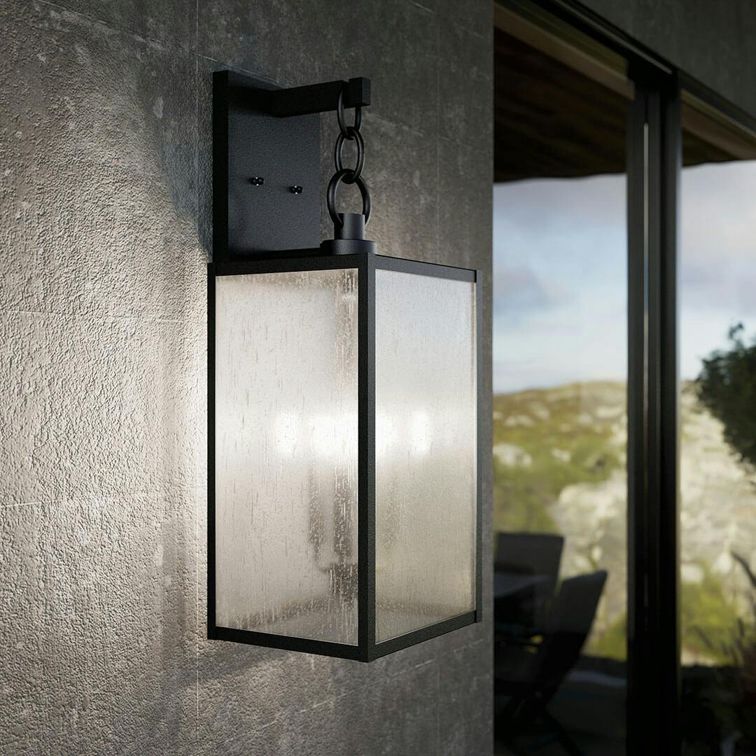 Patio in day light with the Lahden 26" 3 Light Outdoor Wall Light with Clear Seeded Glass in Textured Black