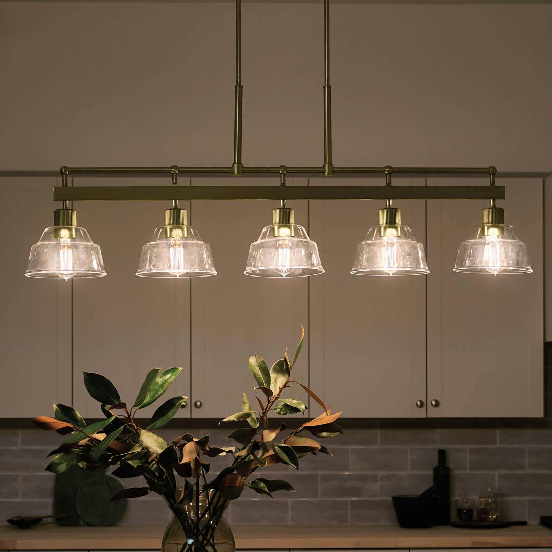 Night time kitchen with Eastmont™ 5 Light Linear Chandelier Brushed Natural Brass and Walnut Wood