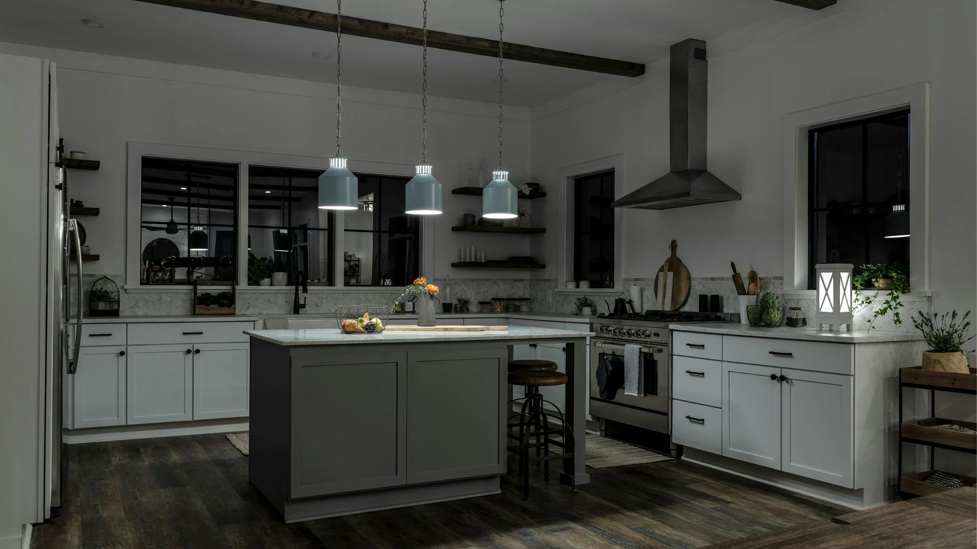 A kitchen with tape lights, shelf lighting, kicktoe lighting, and Montauk pendants, with just the pendant lights turned on at night
