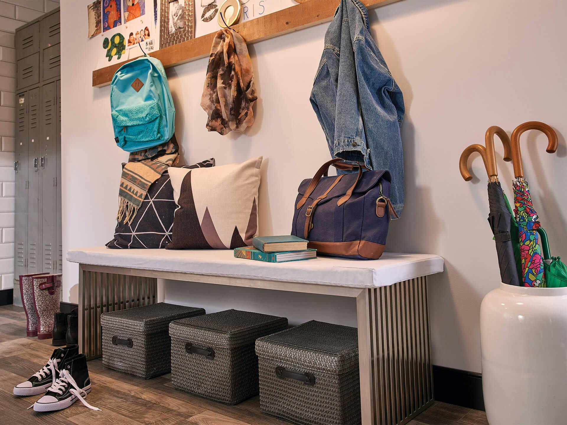 Bench in mudroom surrounded by household items such as shoes, backpacks, umbrellas, books, etc.