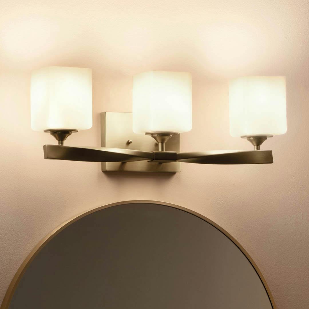 Night time bathroom with Marette 23 inch 3 Light Vanity Light with Satin Etched Cased Opal Glass in Champagne Bronze