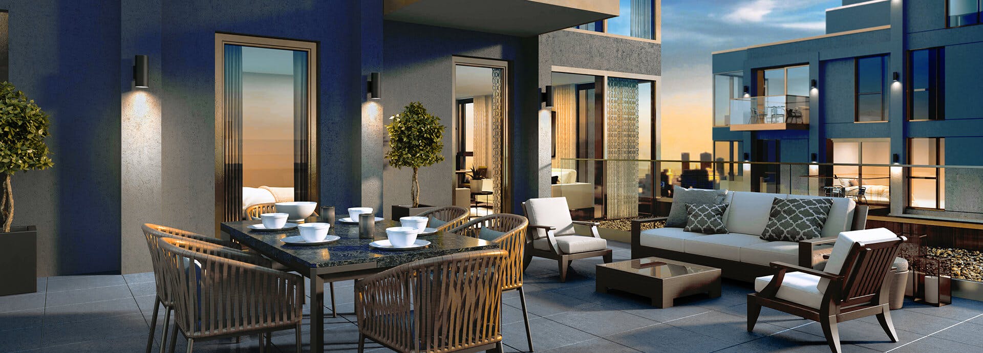 Large high rise patio in the evening with variety of couches and tables and sconce lights