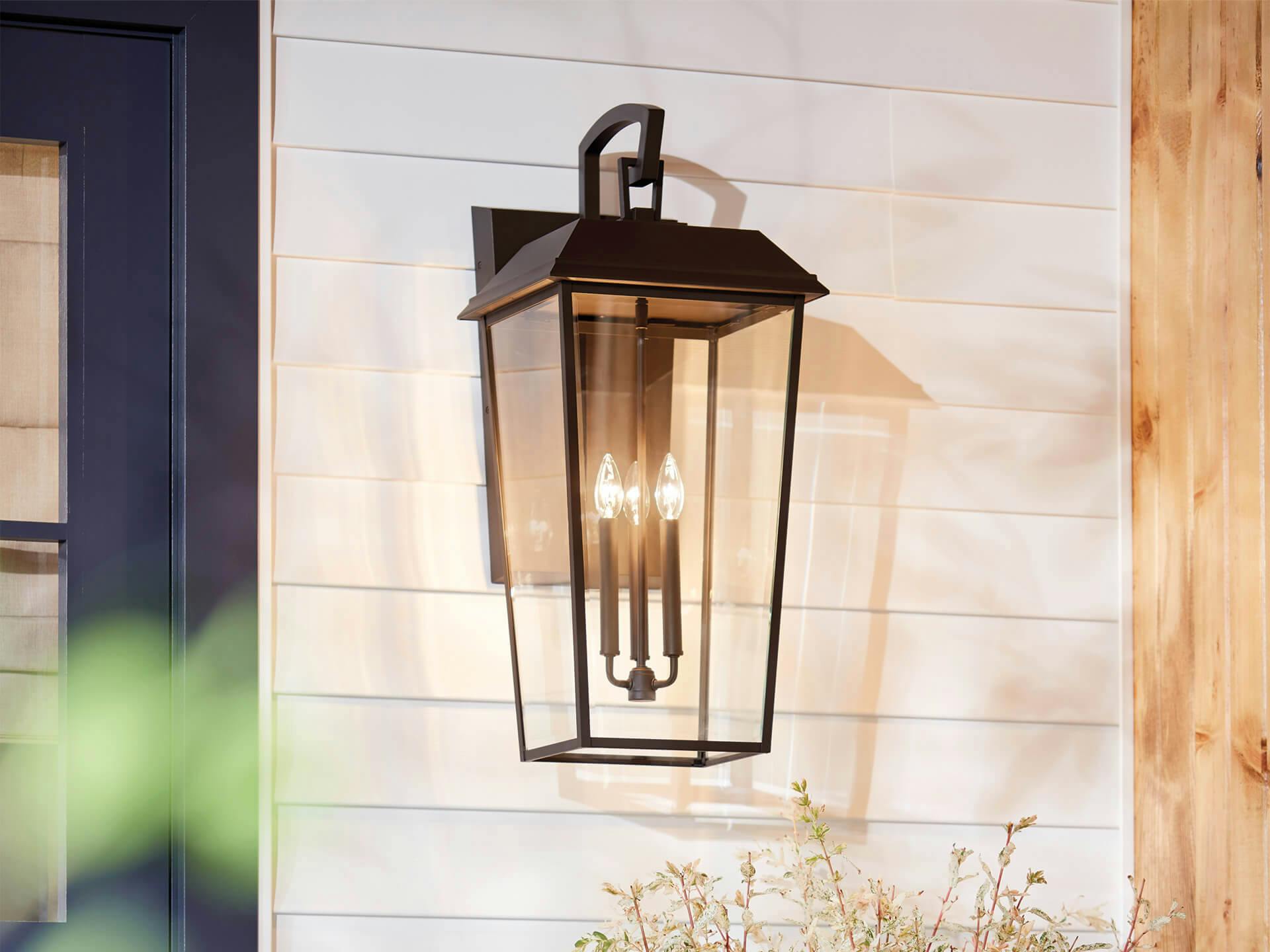White sided house exterior with Mathus 3-light wall light in old bronze finish