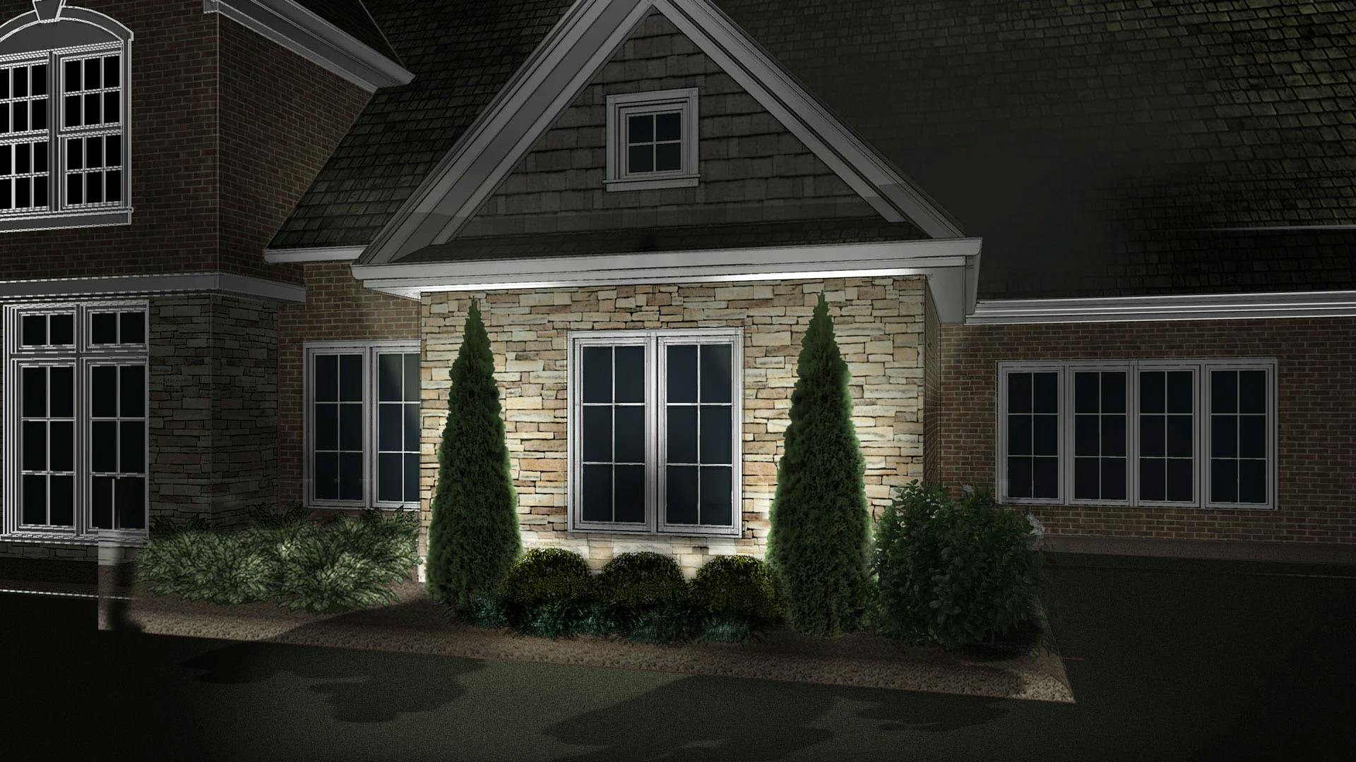 An exterior of a home at night with uplights behind tall shrubs.