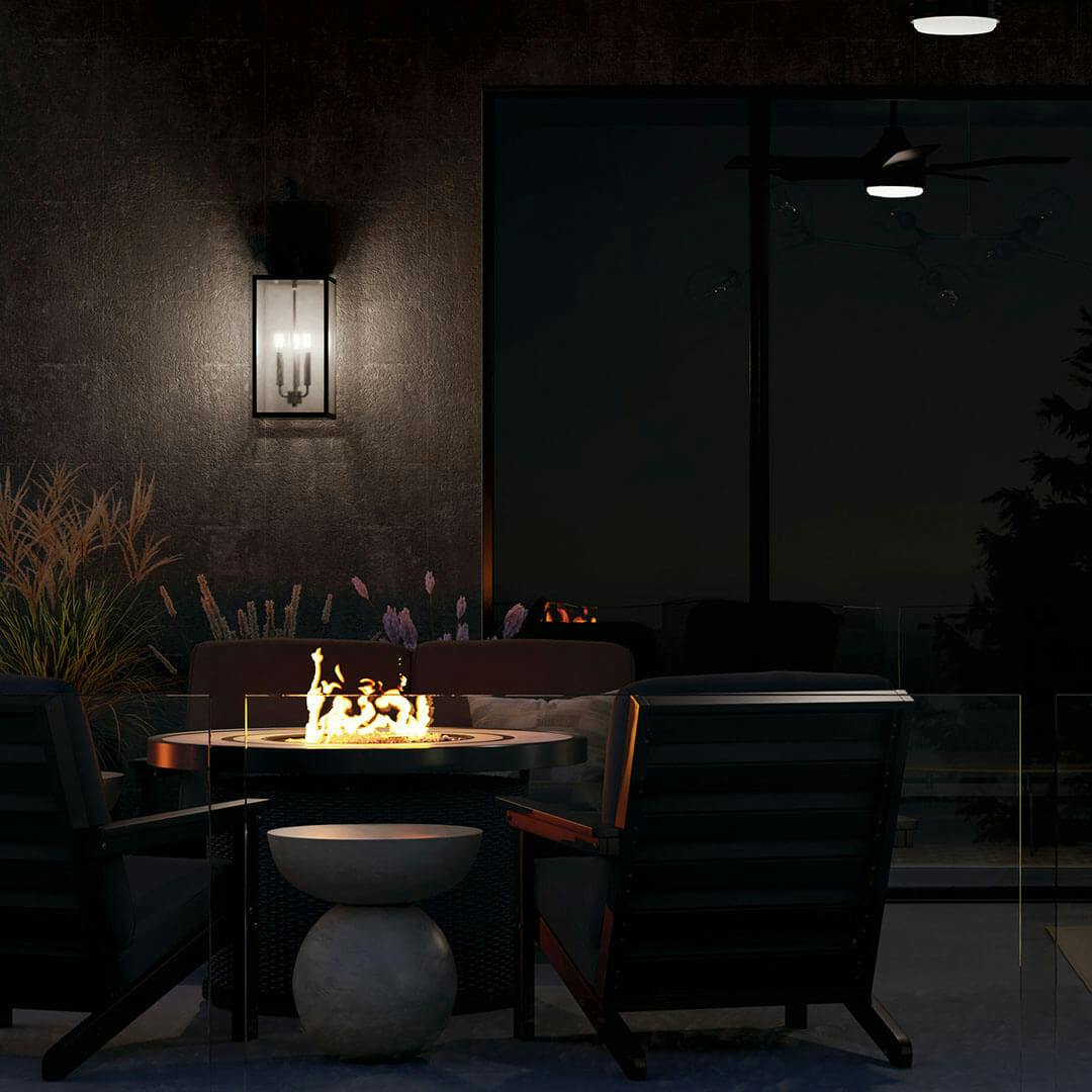 Patio at night with the Lahden 26" 3 Light Outdoor Wall Light with Clear Seeded Glass in Textured Black