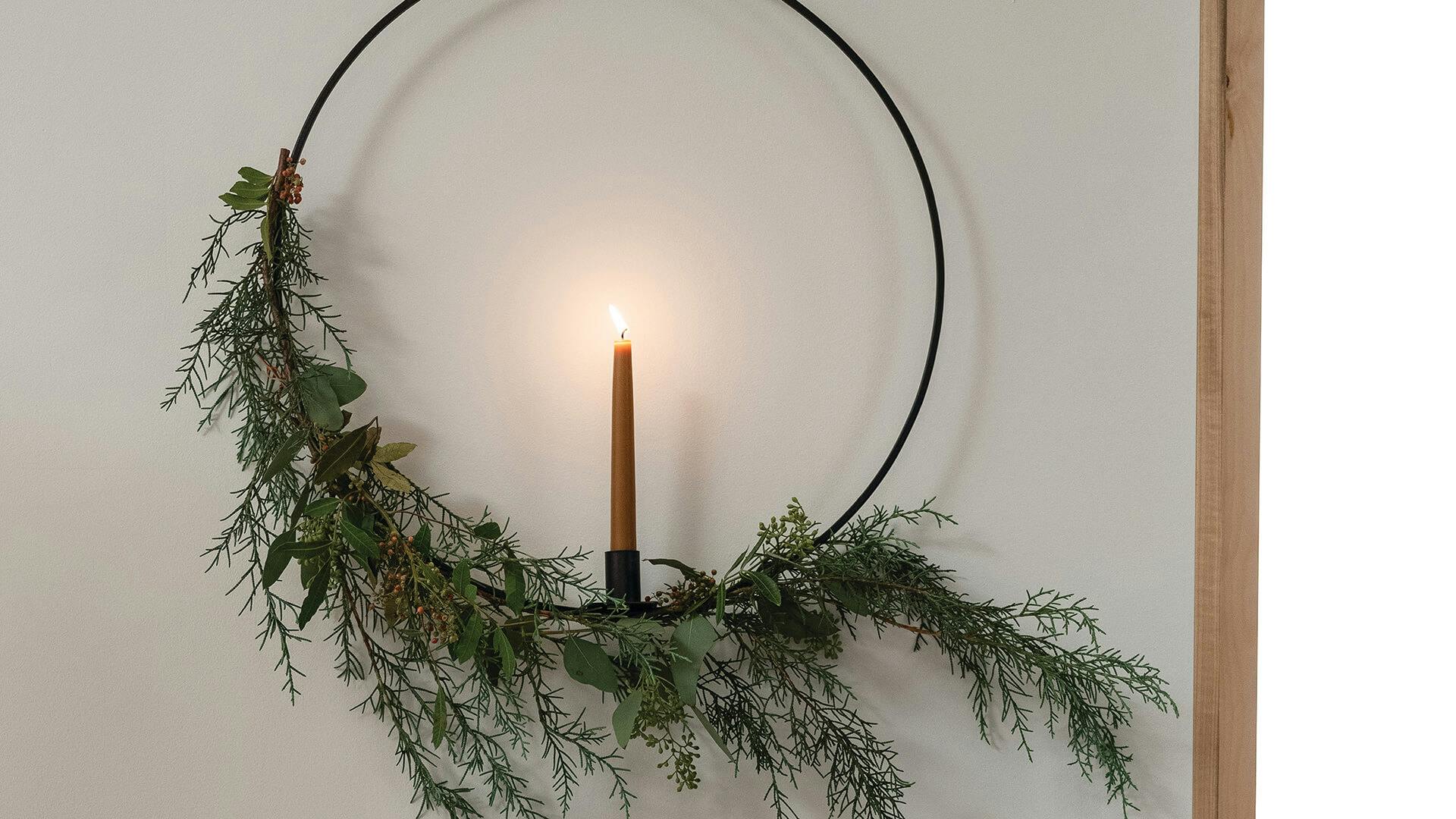 Close up of a lit candle in a ring style wreath in a living room