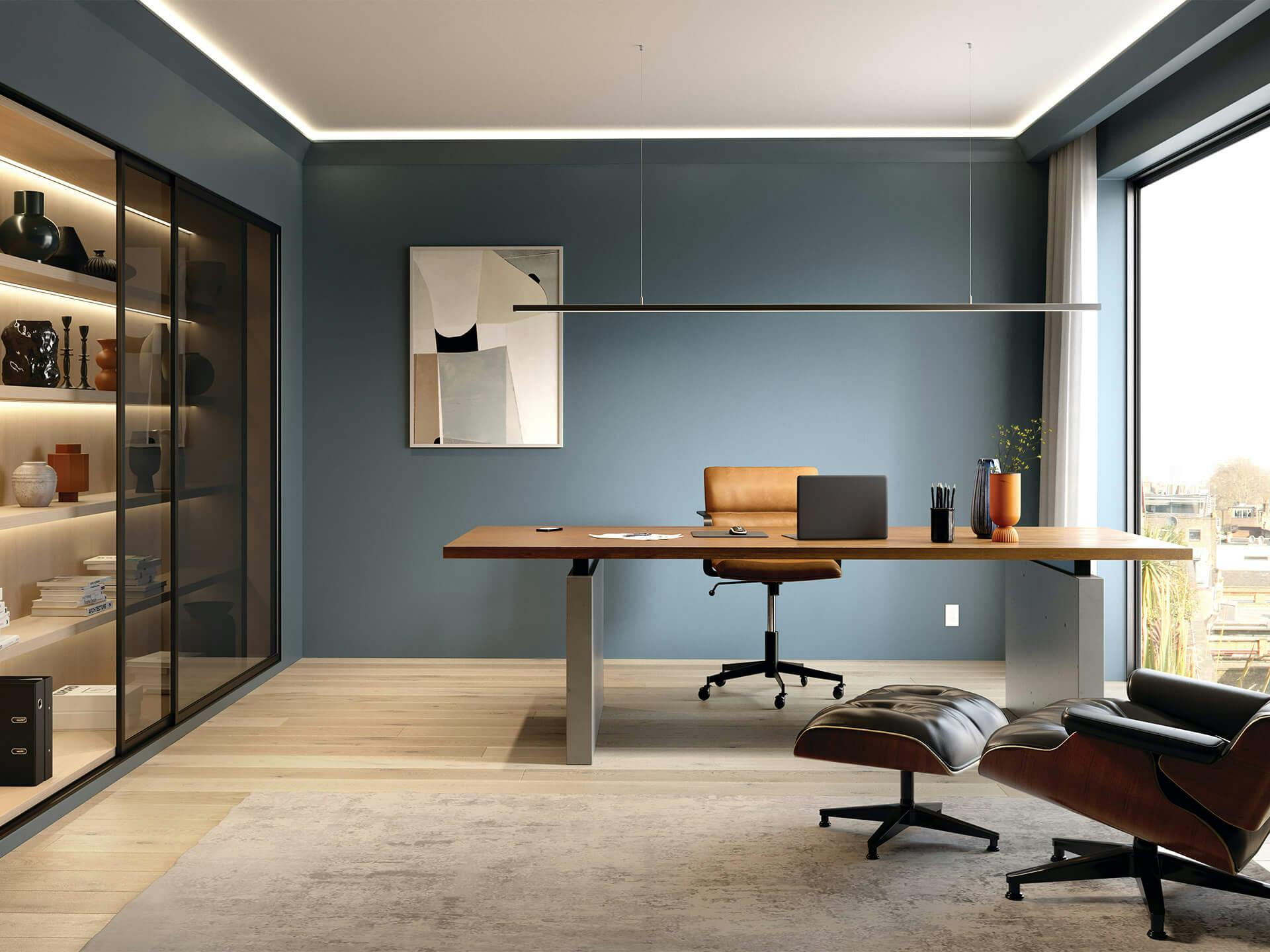 Office with blue wall, wide desk and overhead channel lighting.