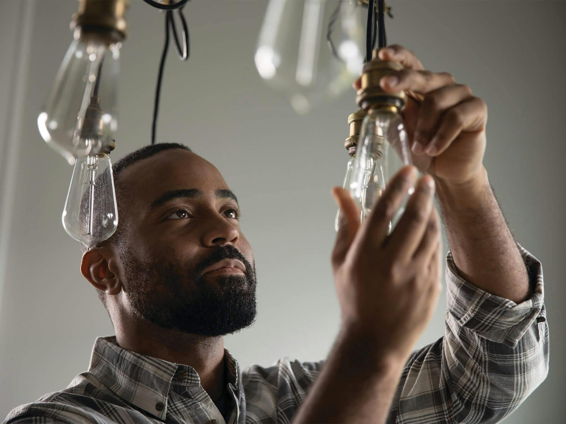 Man changing hanging light bulbs