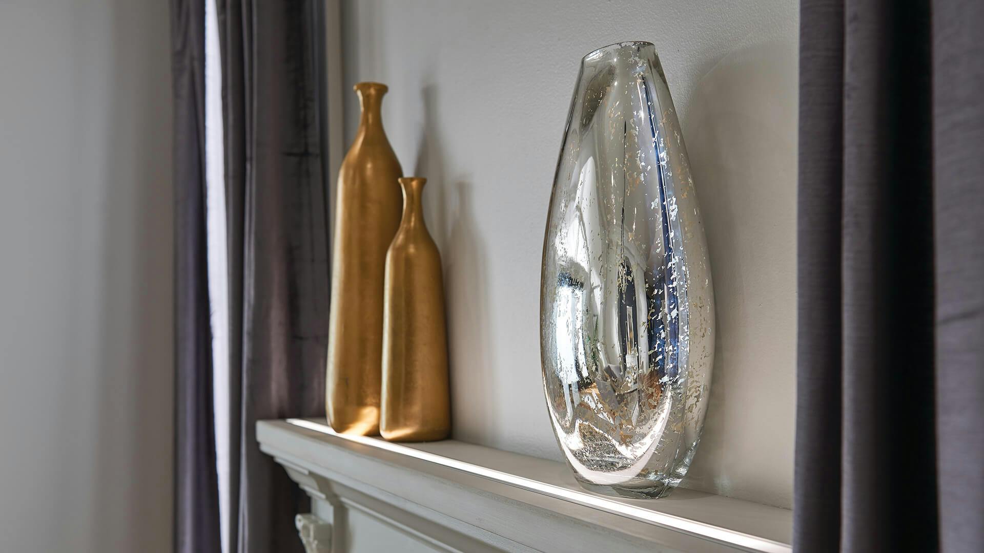 Gold and silver unique shaped vases on a mantle between two windows