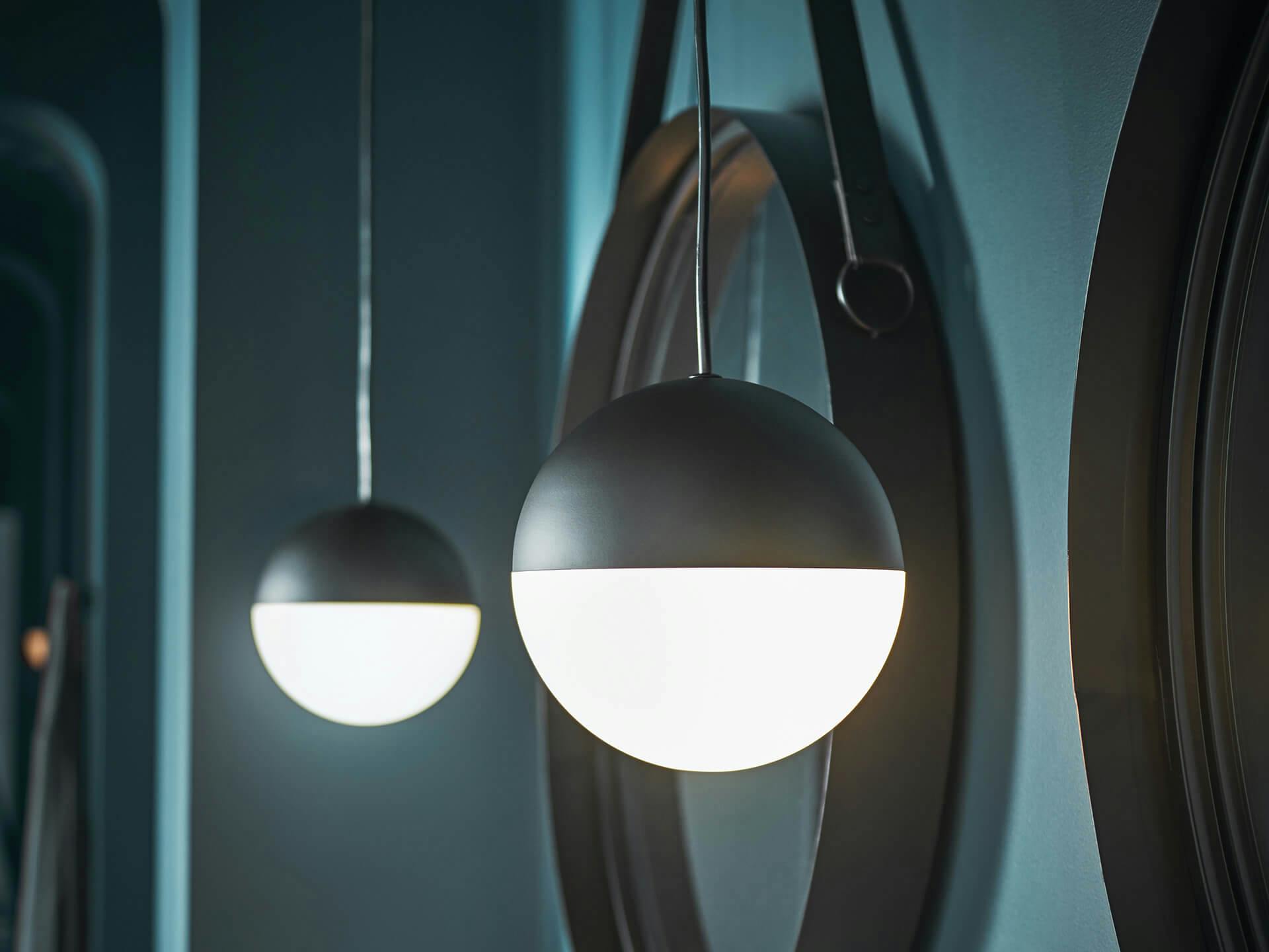 Bathroom at night with a close up on two moonlit black finish pendants in front of two round mirrors