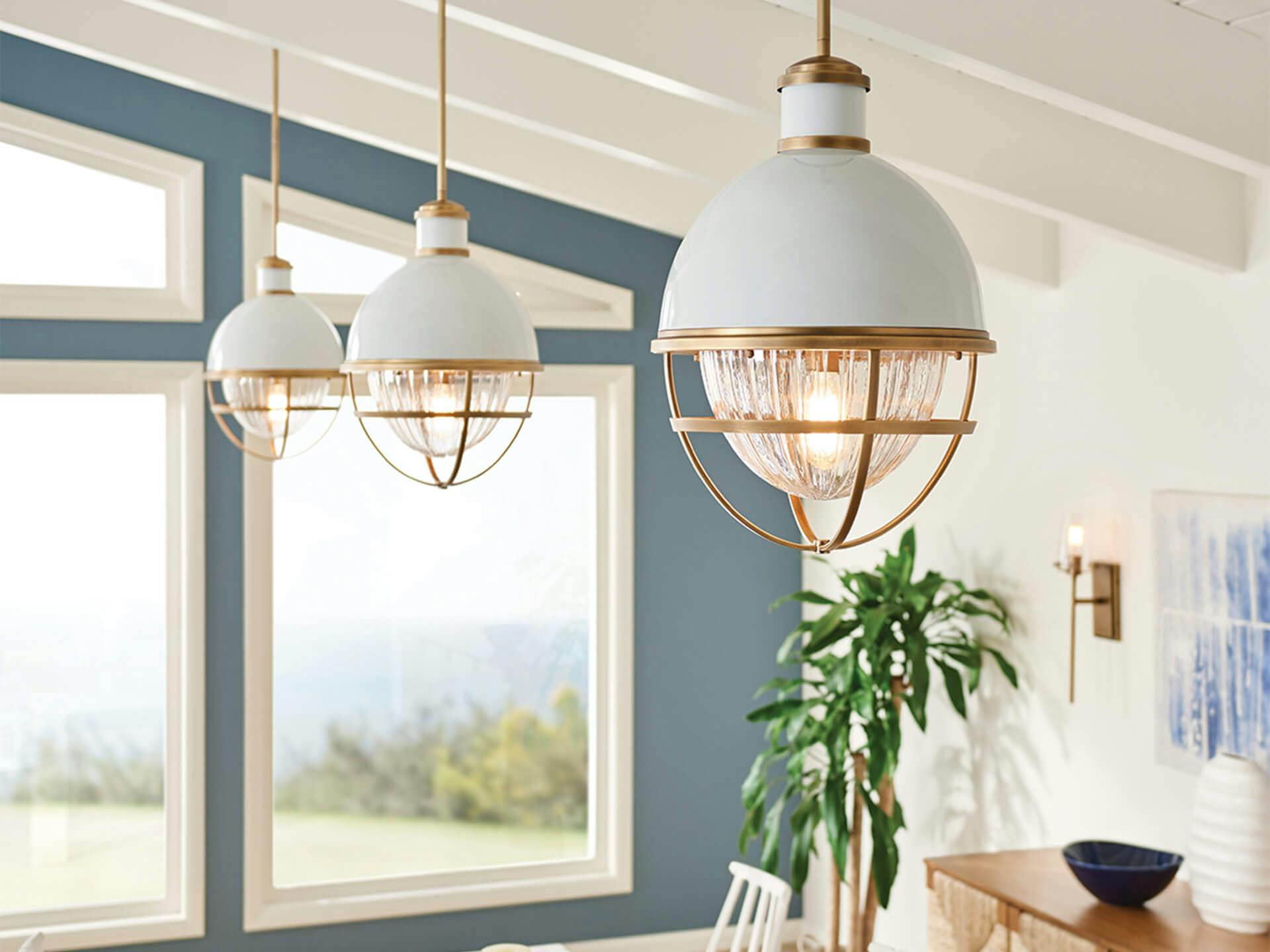 Three Tollis Alton pendants with white finish in a coastal style living room in the daytime turned on