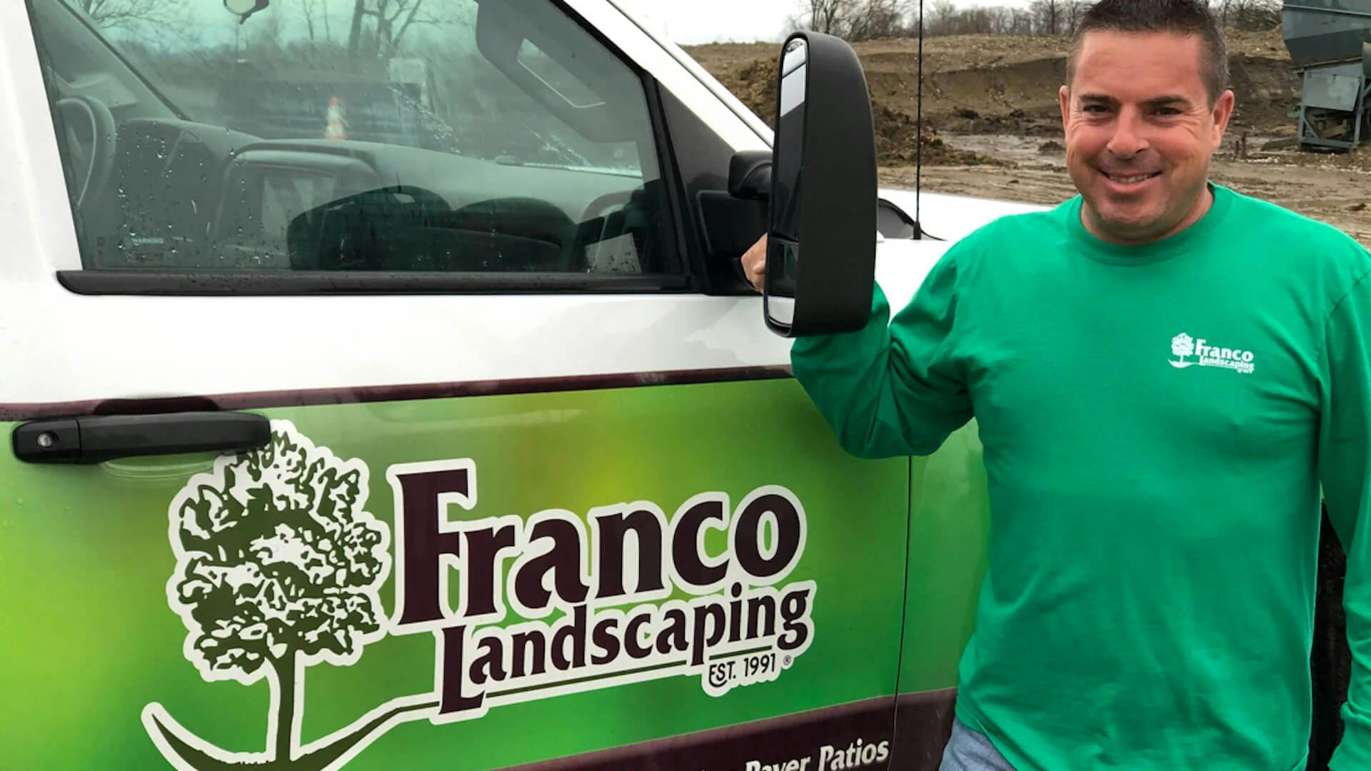 Man smiling next to a truck that is branded Franco Landscaping