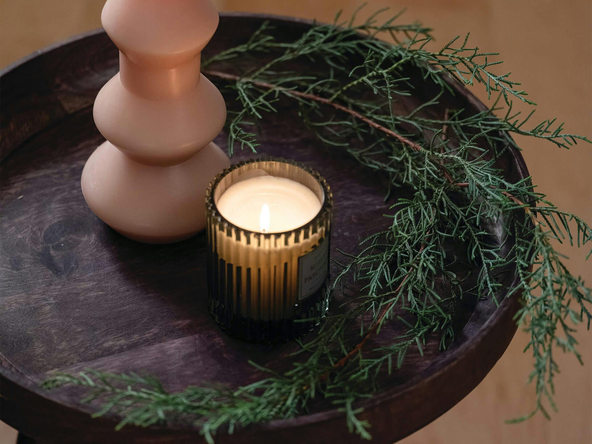 Decorative image of a small round side table with a lit candle and vase