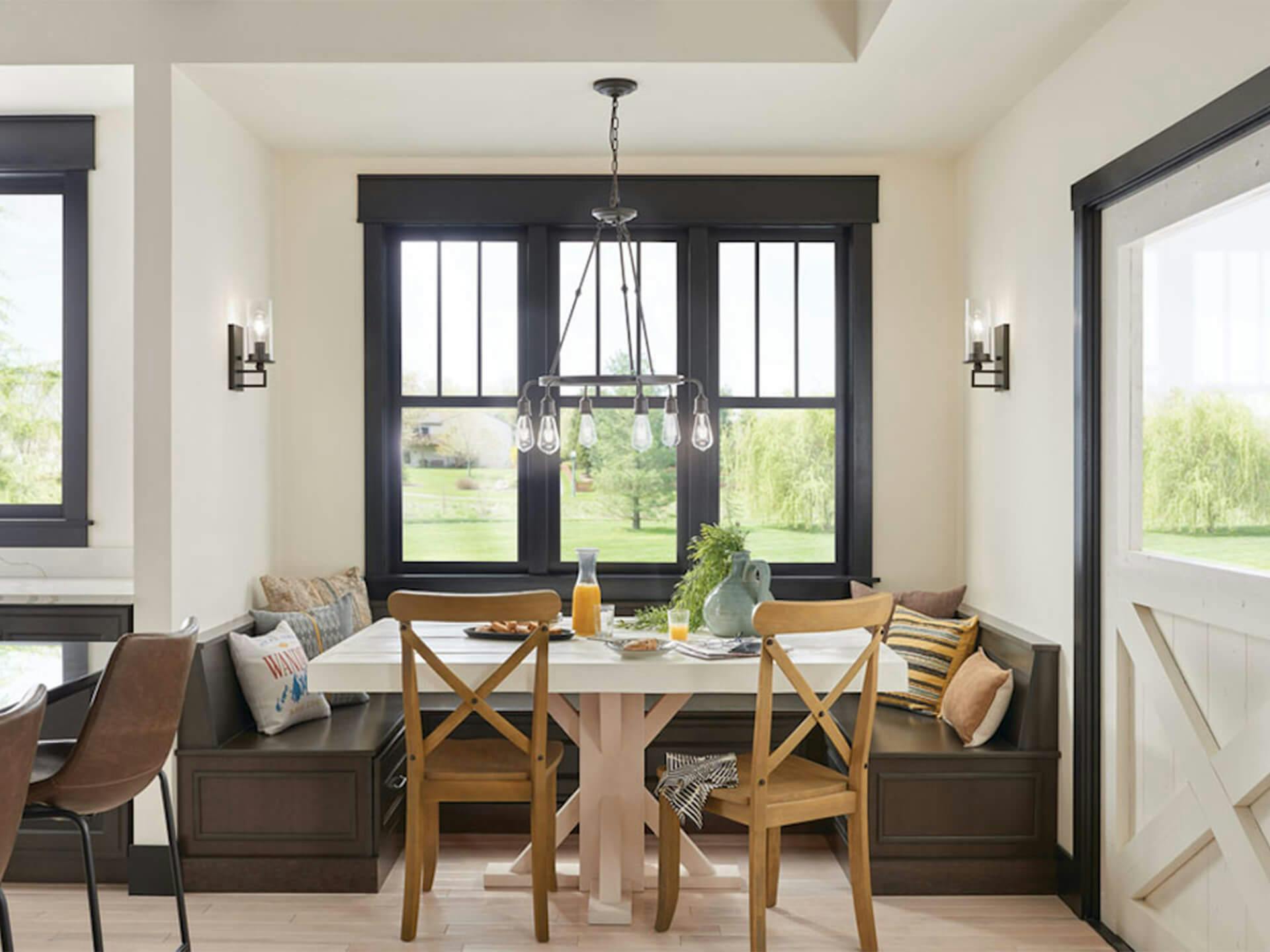 A breakfast nook with an Olde Bronze Lucien Chandelier above a table turned on in the daytime