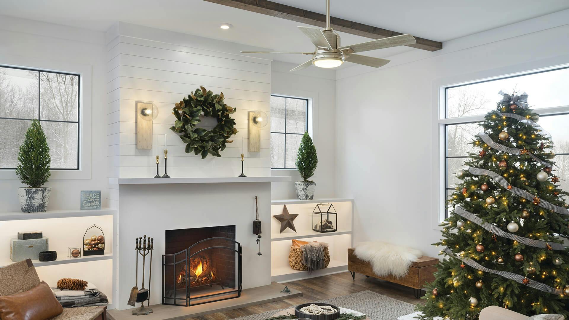 Living room during the day with holiday decor including a Christmas tree and wreath over a lit fireplace