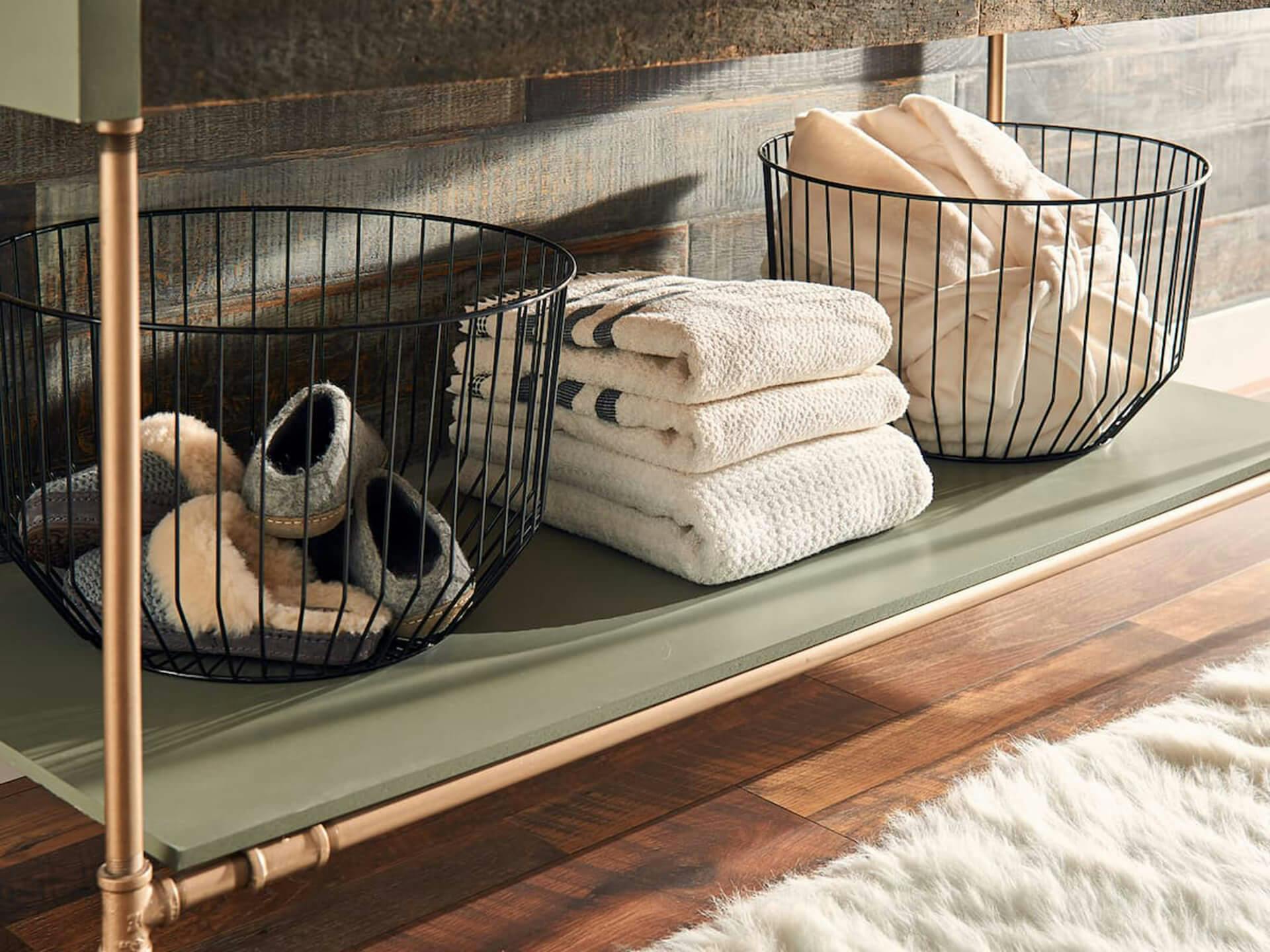 Close up of a green bathroom shelf with towels and baskets