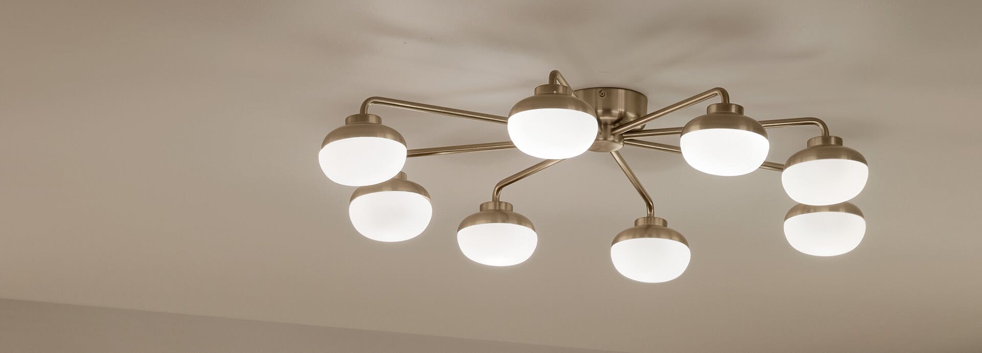 Close-up of a lit Remy flush mount light in champagne bronze on a kitchen ceiling
