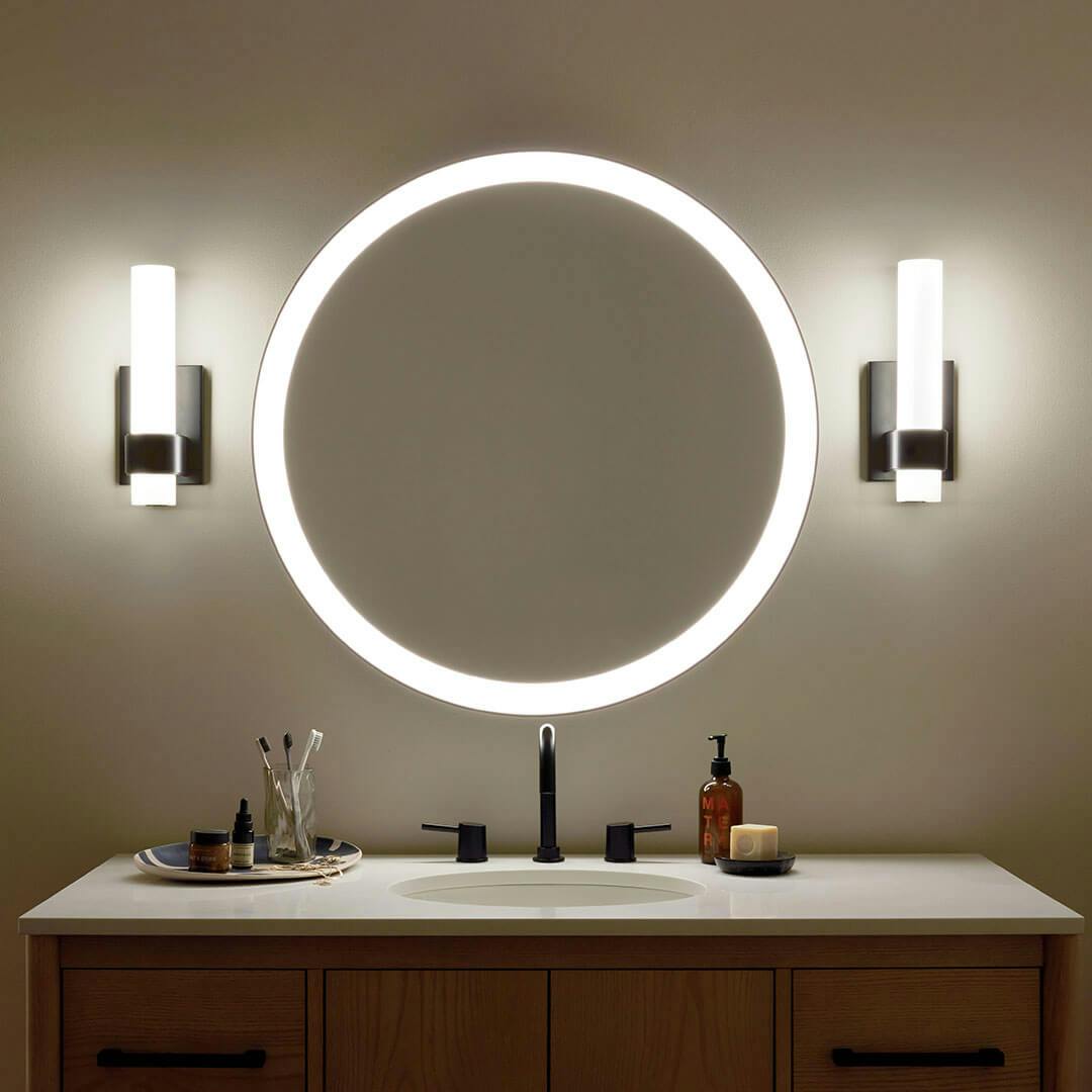 Bathroom in the night time with the Izza 13.25 Inch 1 Light LED Wall Sconce in Matte Black