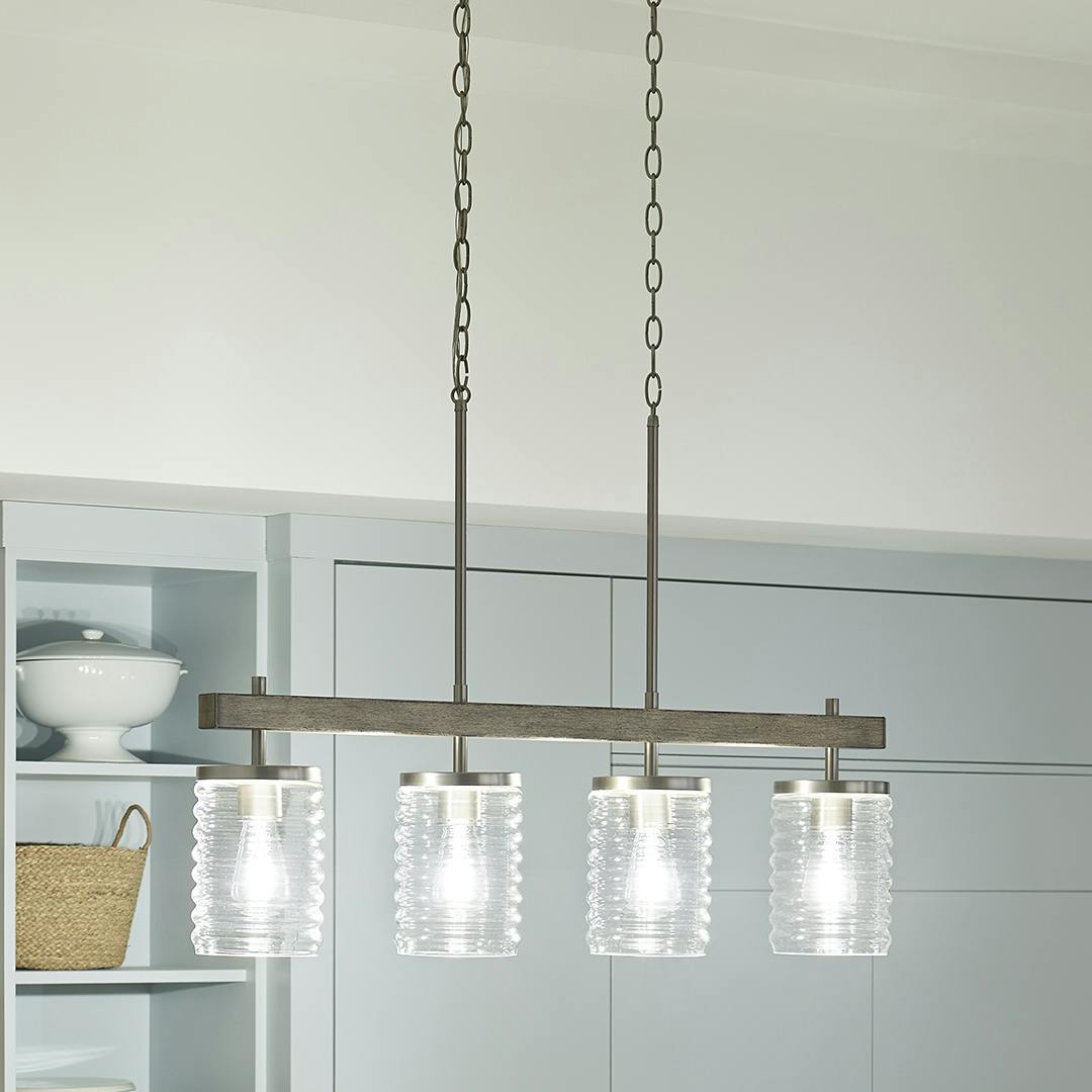Night time kitchen with Maritime 4 Light Linear Chandelier in Brushed Nickel and Distressed Antique Gray with Ribbed Glass