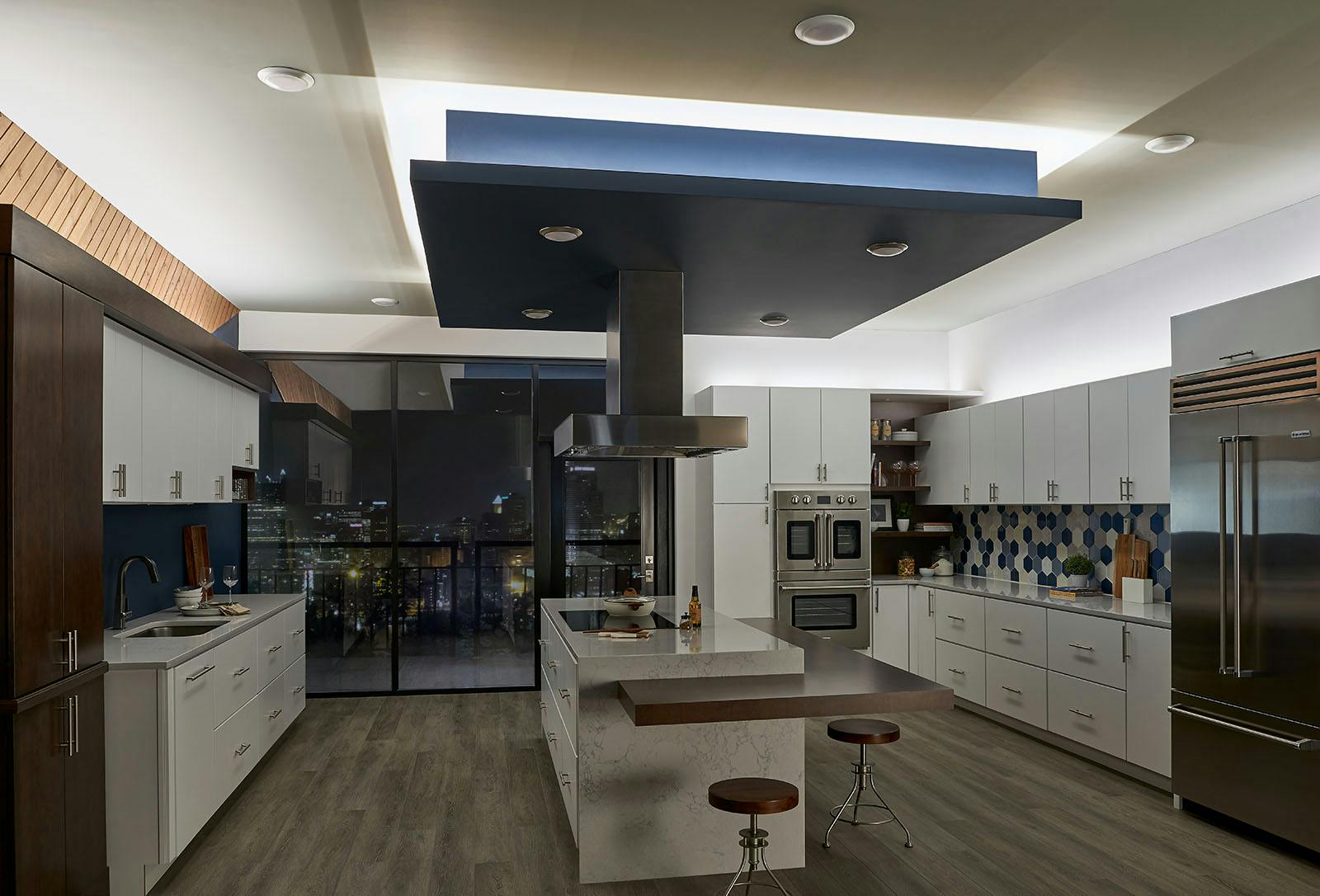 Modern white kitchen with blue, wood, and stainless steel accents in an urban setting with only tape lighting turned on