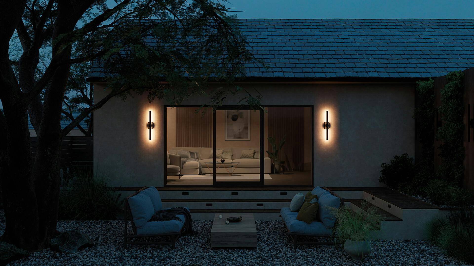 Patio with large glass sliding door at night with 2 nocar wall lights in black finish turned on