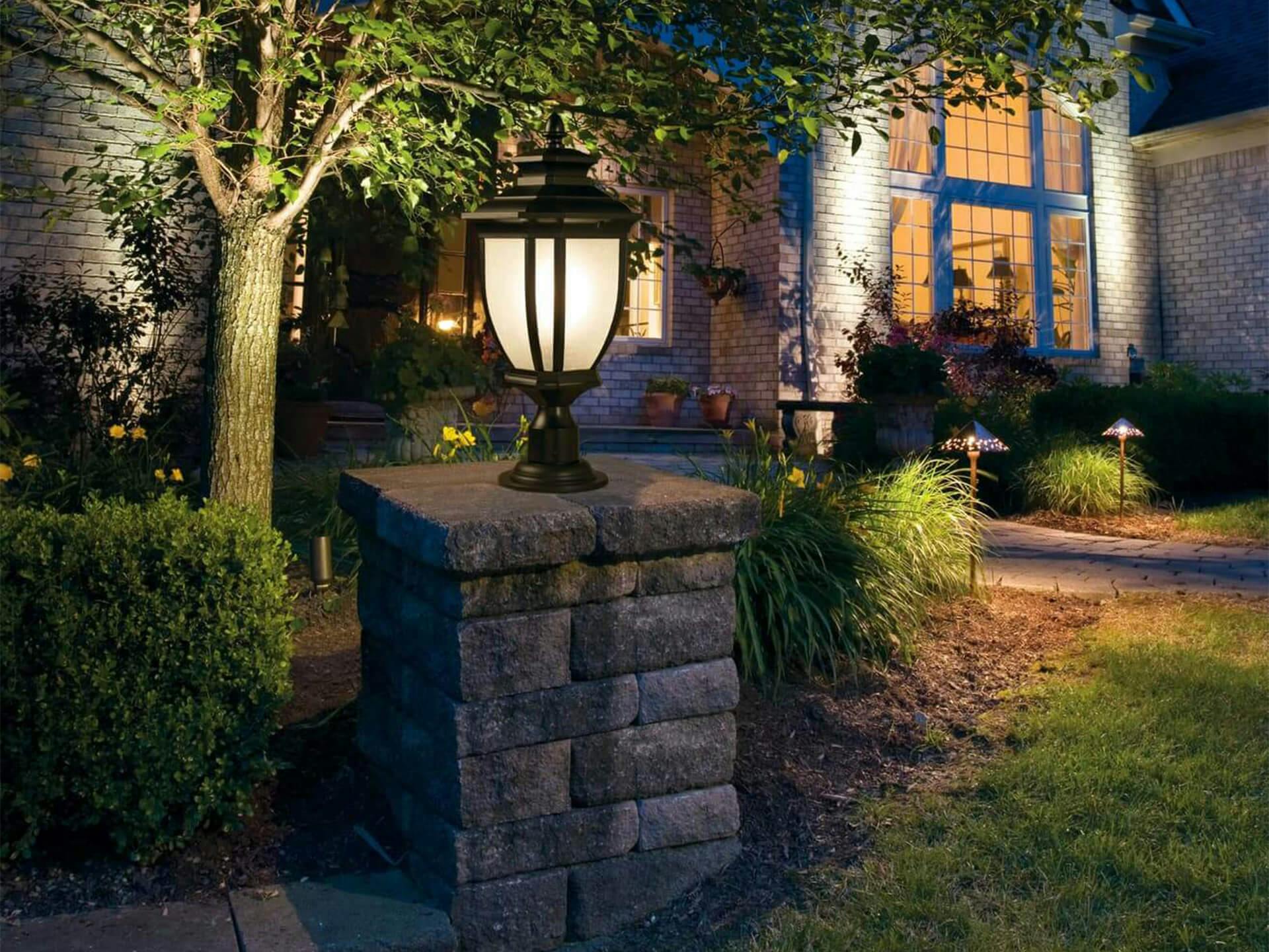 Exterior image of a front yard with a post light lighting up the yard during the night