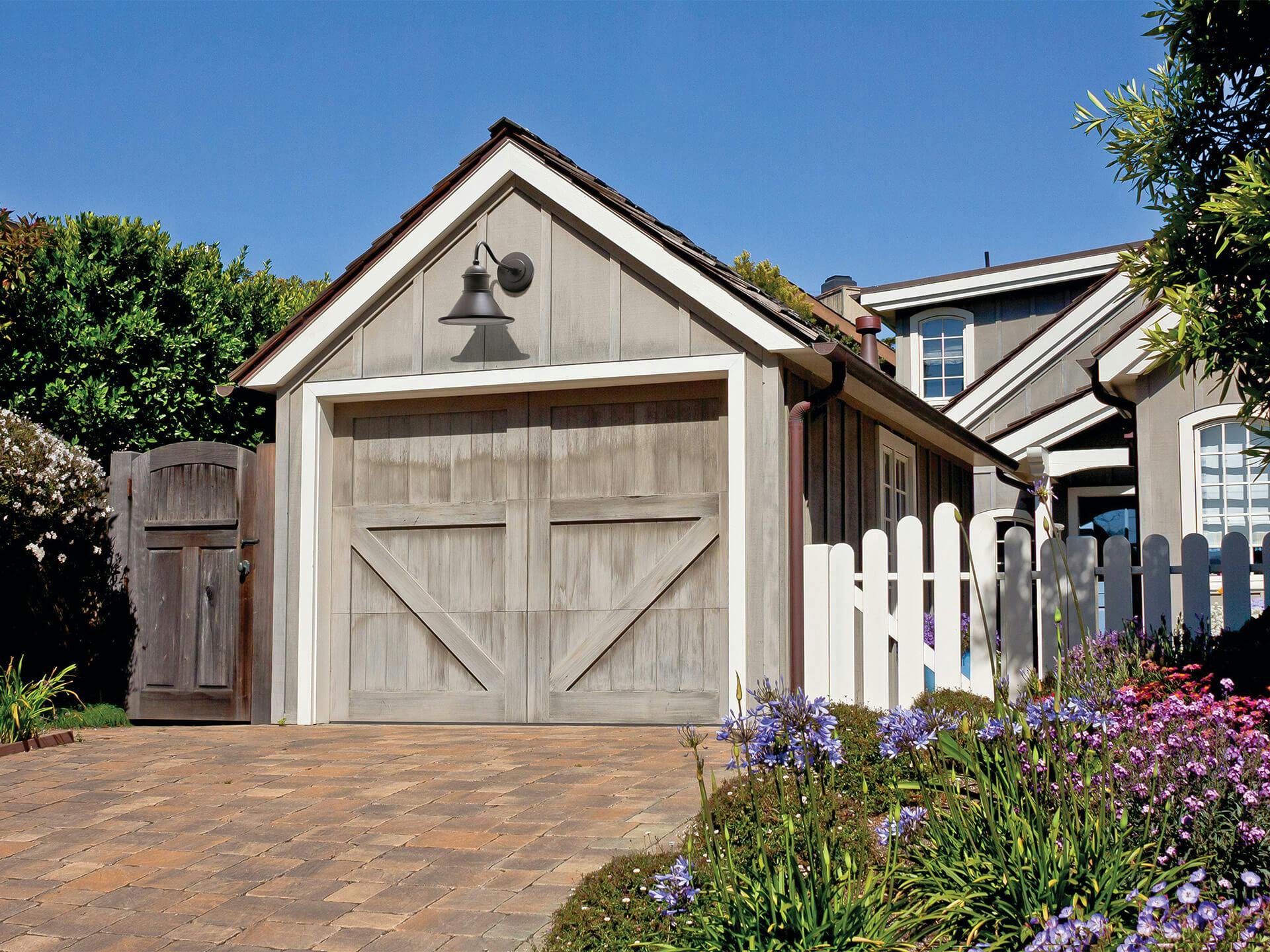Exterior image of a garage door with a Northland exterior wall light above the garage door in the daytime 