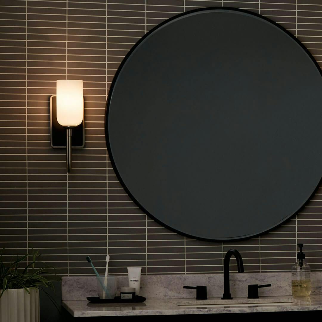 Night time bathroom with the Solia 13.5 Inch 1 Light Wall Sconce with Opal Glass in Brushed Nickel with Black