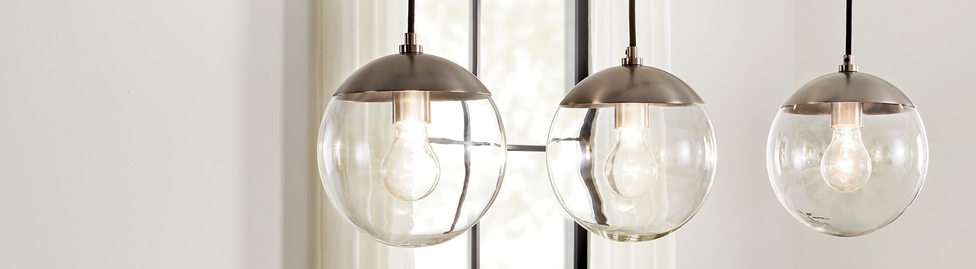 Close-up of three Malone hanging lights against a white background with a window