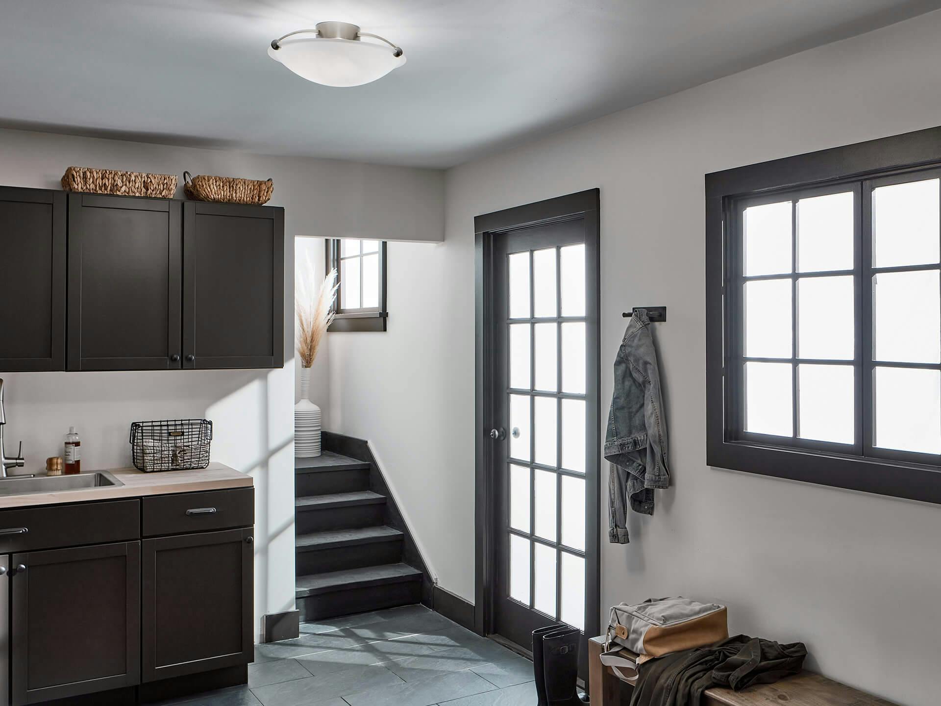 mudroom with sunlight through the door and windows while a 3 Light Flush Mount shines above