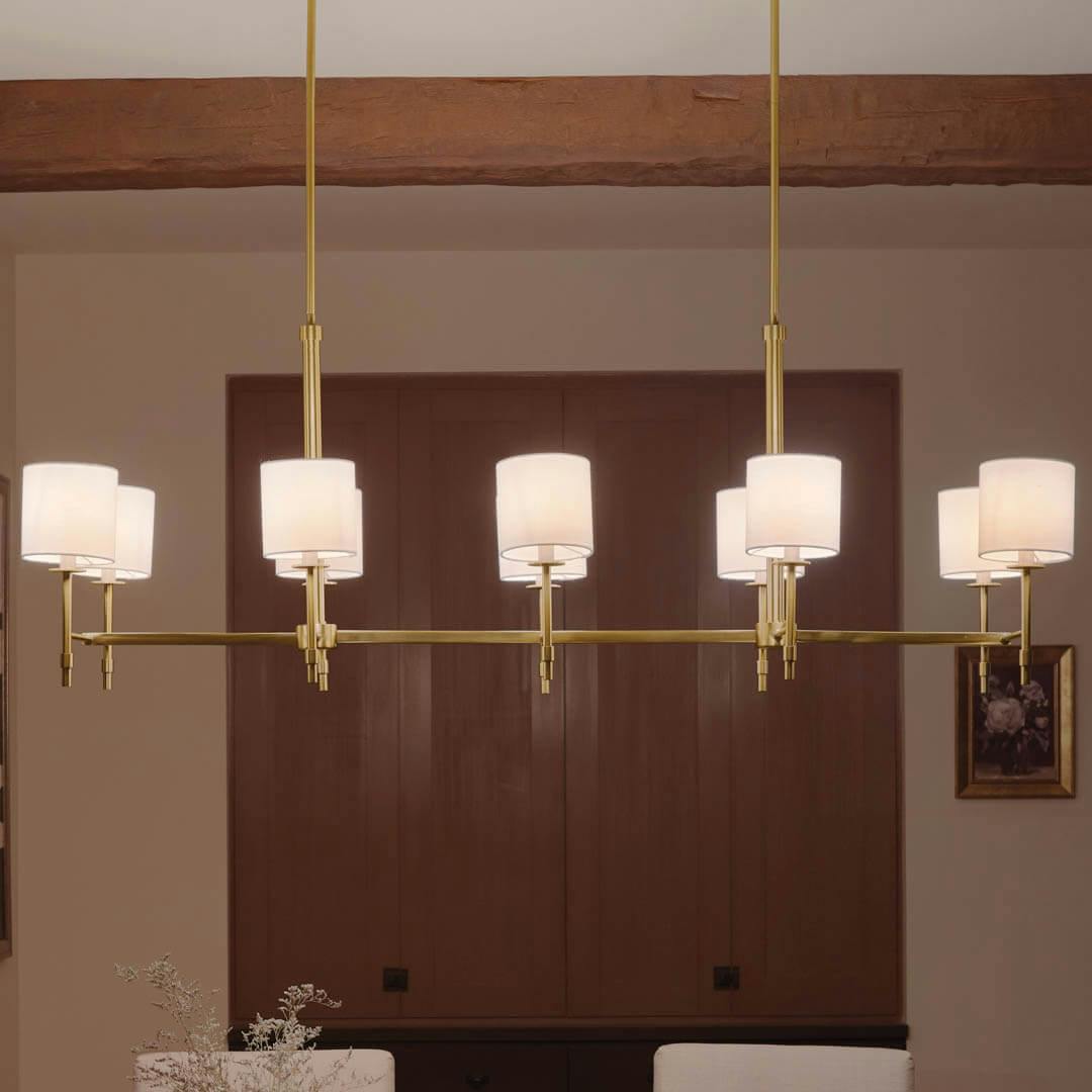Night time dining room with Ali 56.5" 10 Light Linear Chandelier Brushed Natural Brass