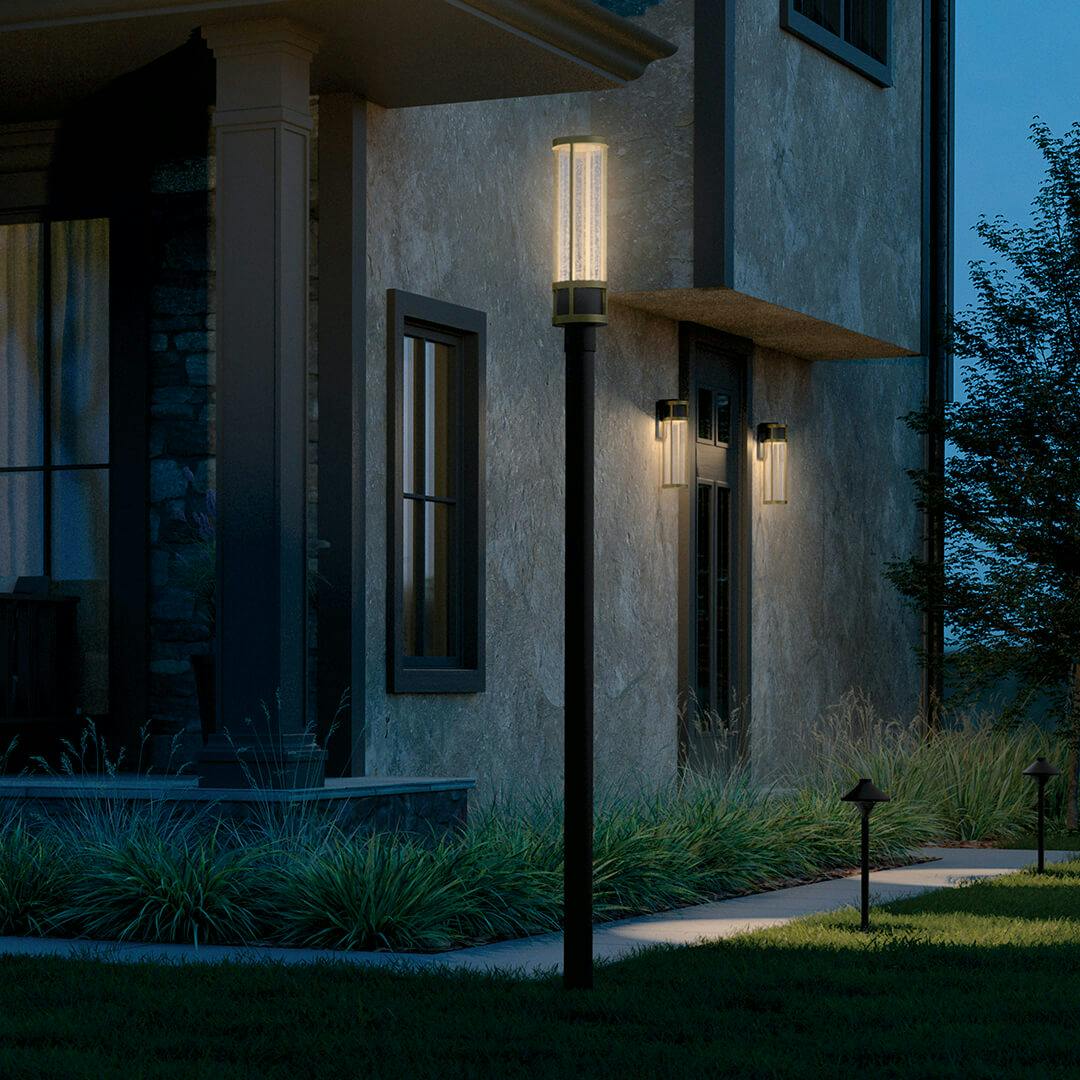 Stone exterior at night with the Camillo 20" LED Outdoor Wall Light with Clear Seeded Glass in Textured Black with Natural Br