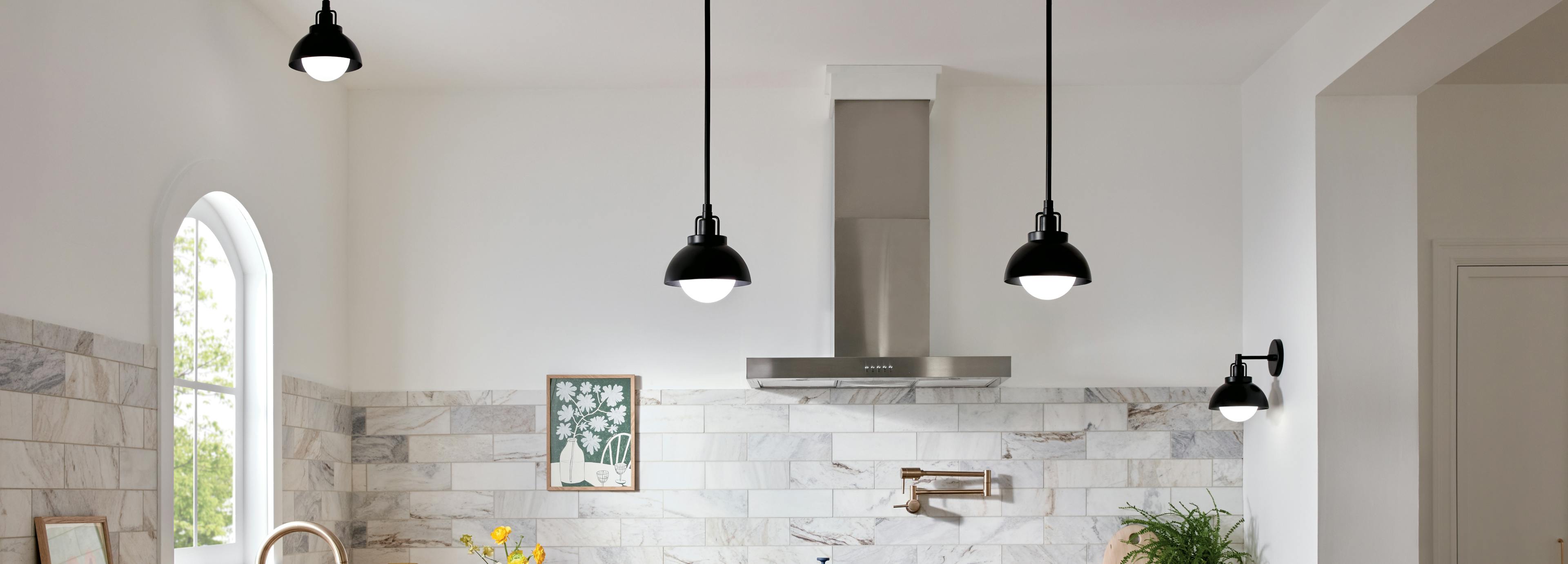 White kitchen during the day with marble wall tiling and black niva pendant lights