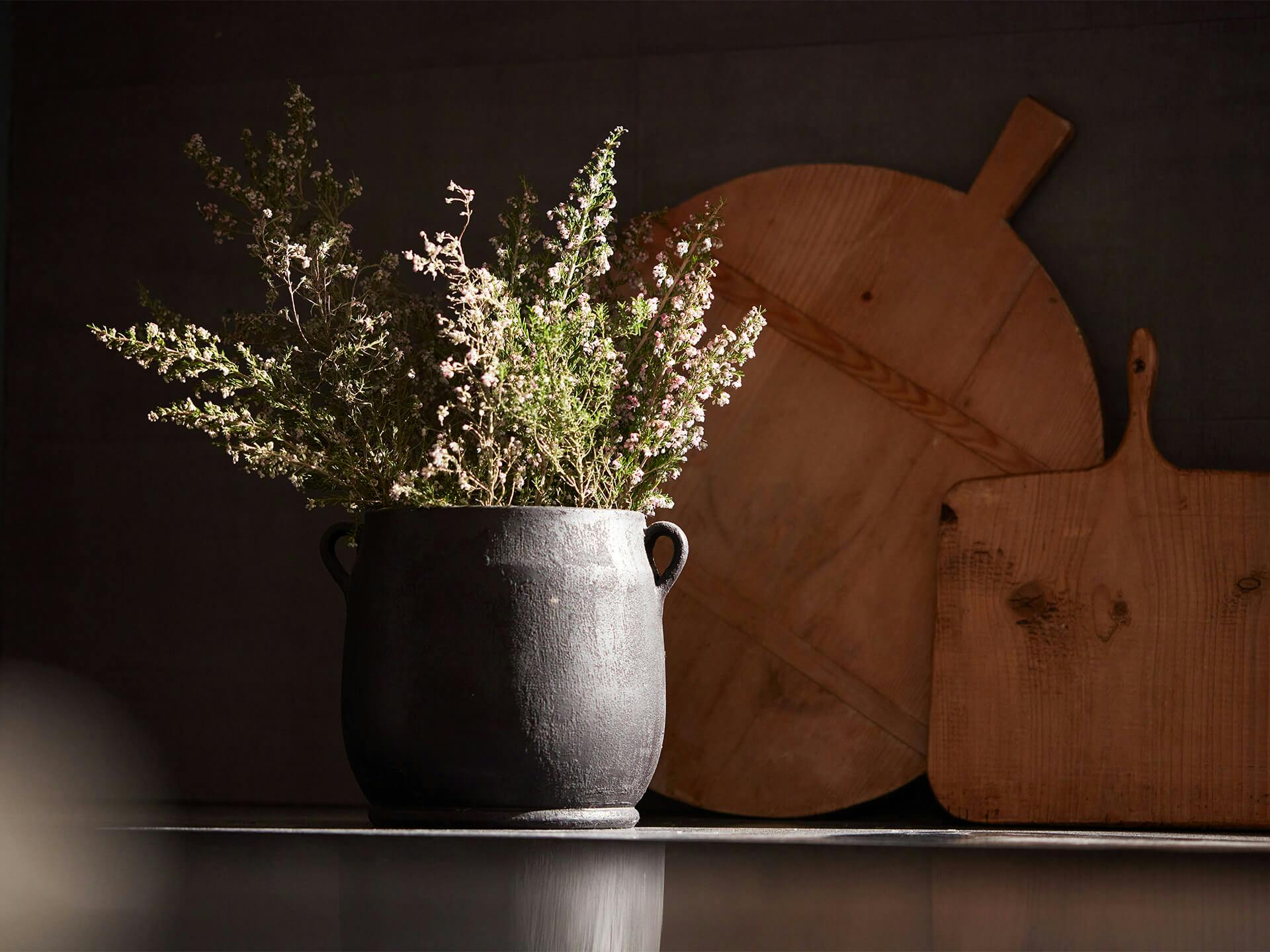 Lifestyle shot of a vase with wildflowers in it and wooden vintage kitchen supplies in the background