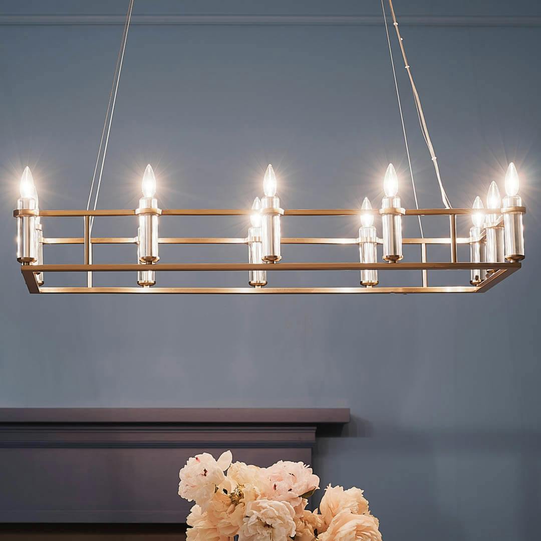 Night time dining room with Rosalind 45.25" 12 Light Linear Chandelier Brushed Natural Brass